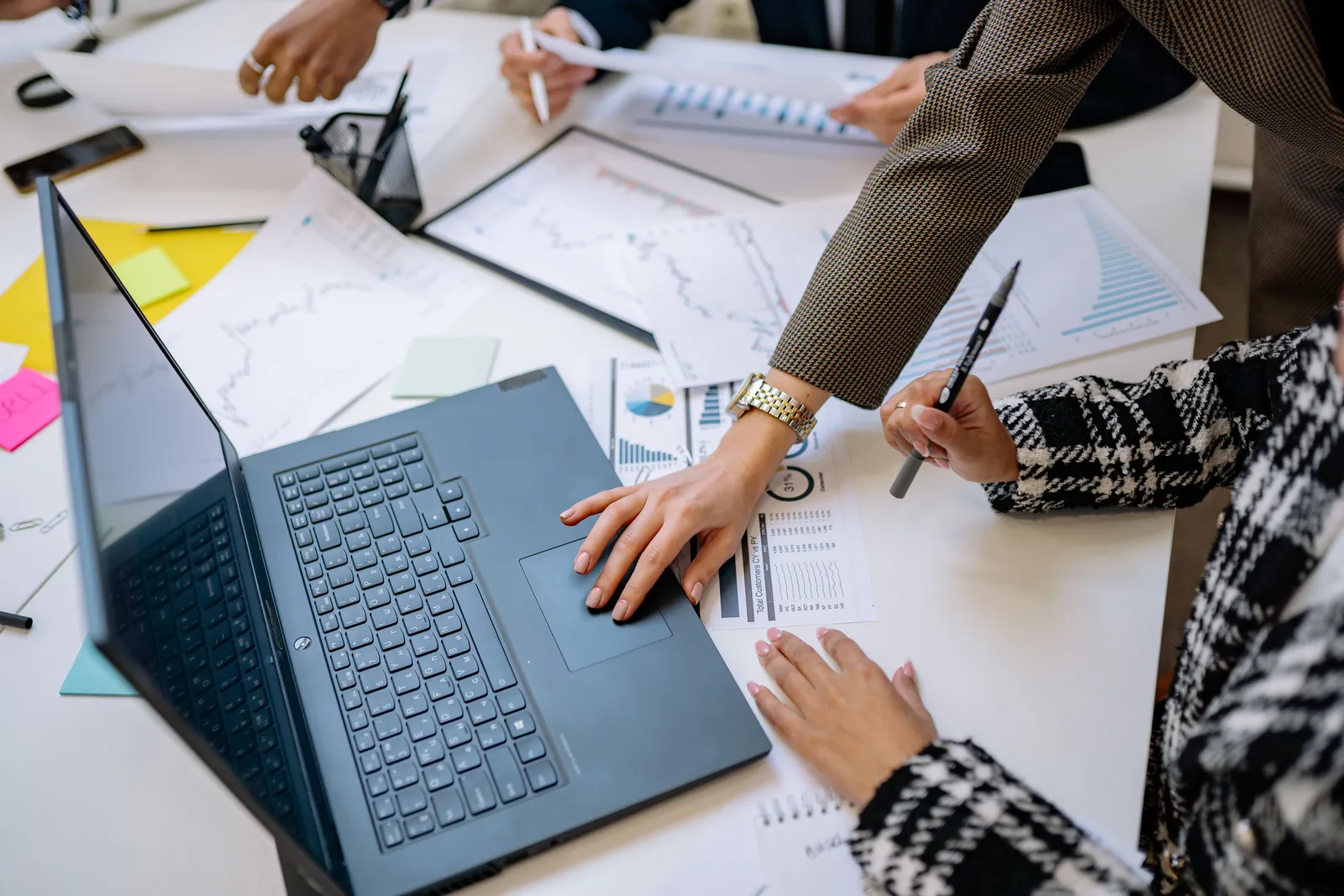 Business team analyzing data and charts during a meeting with a laptop on the table