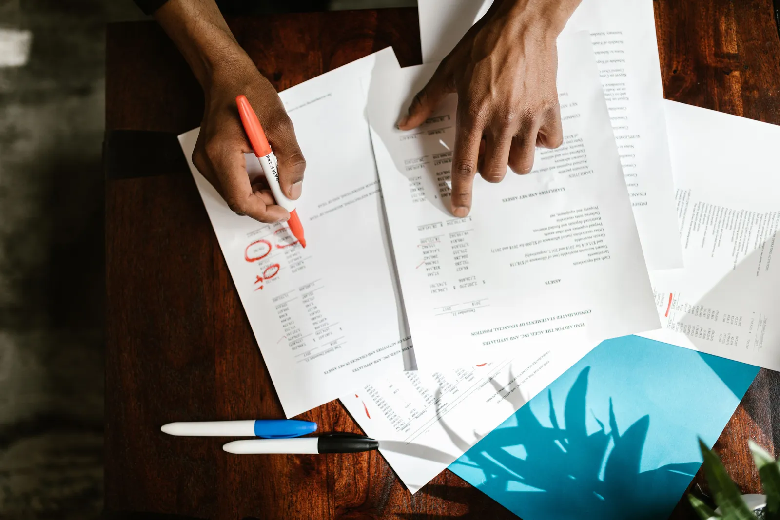 Overhead view of hands highlighting financial documents on a desk