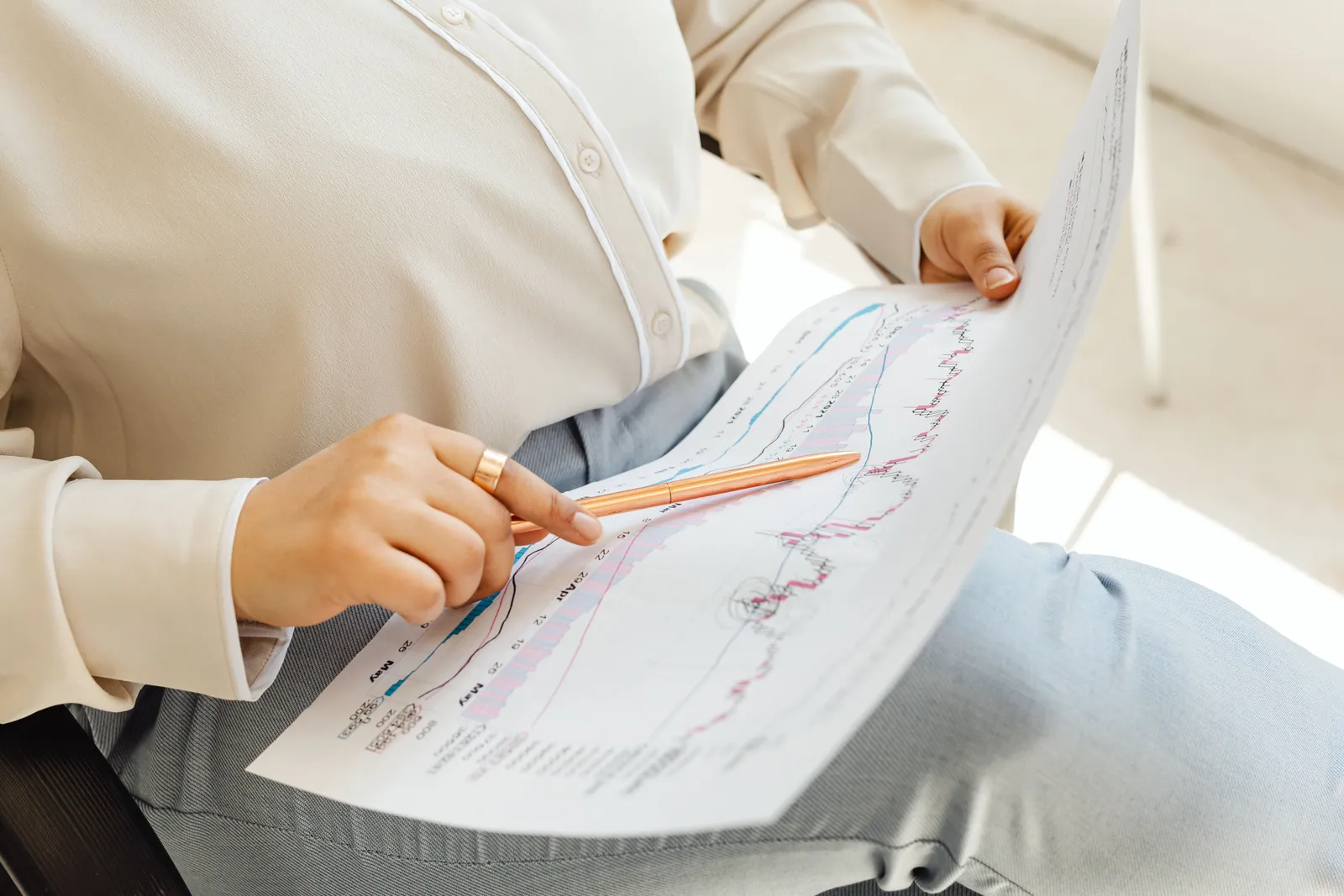 Close-up of hands holding and analyzing finance charts with pen