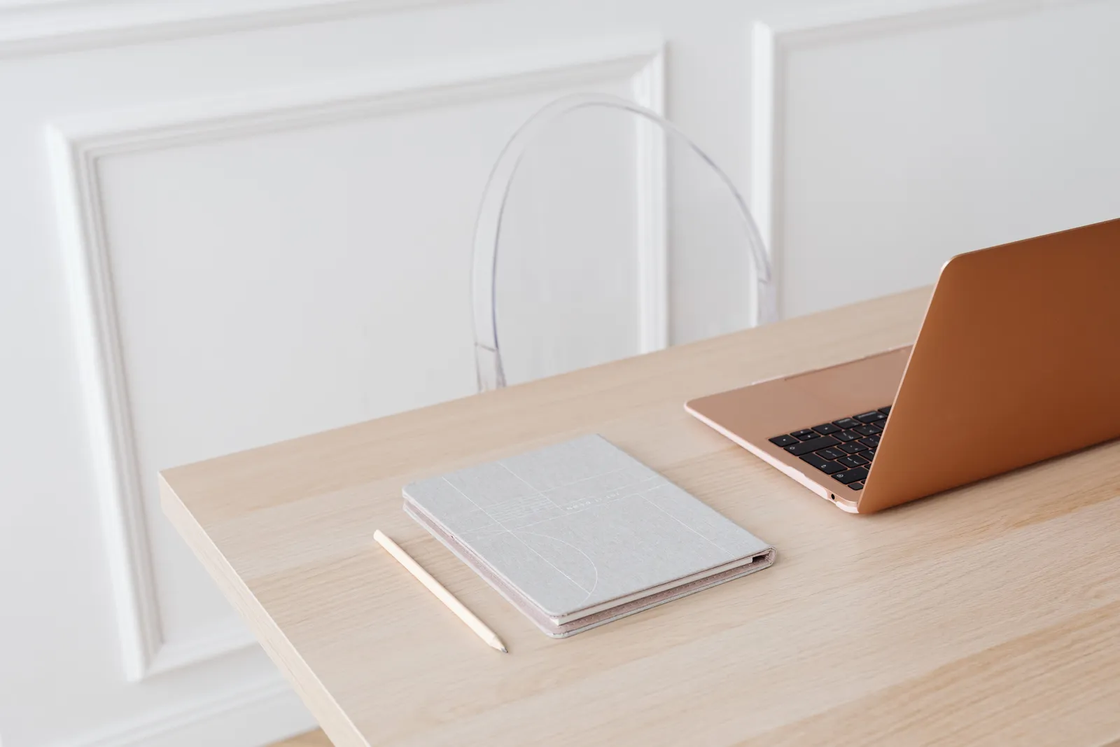 Bright, minimalist setup featuring a laptop and notebook on a wooden desk, perfect for modern workspace inspiration