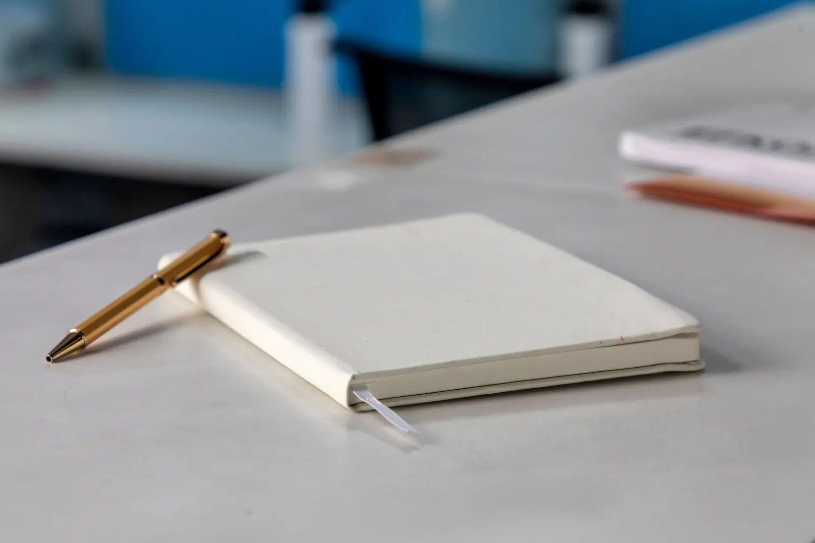 Minimalist white notebook and golden pen on a modern desk setting