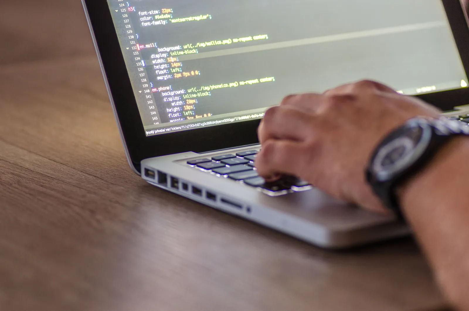 A close-up shot of a person coding on a laptop, focusing on the hands and screen