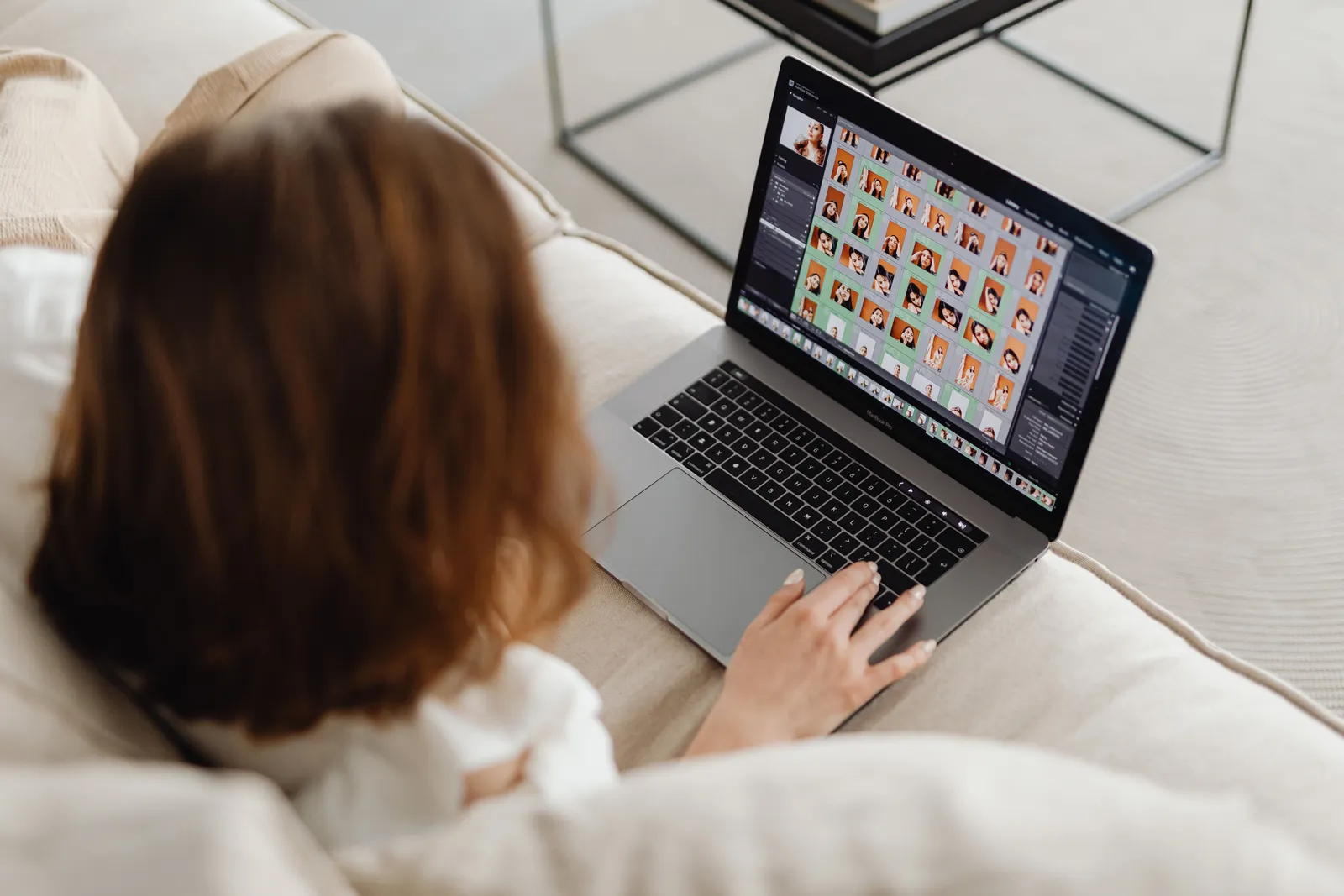 Woman using a laptop with a photo editing gallery, sitting comfortably indoors