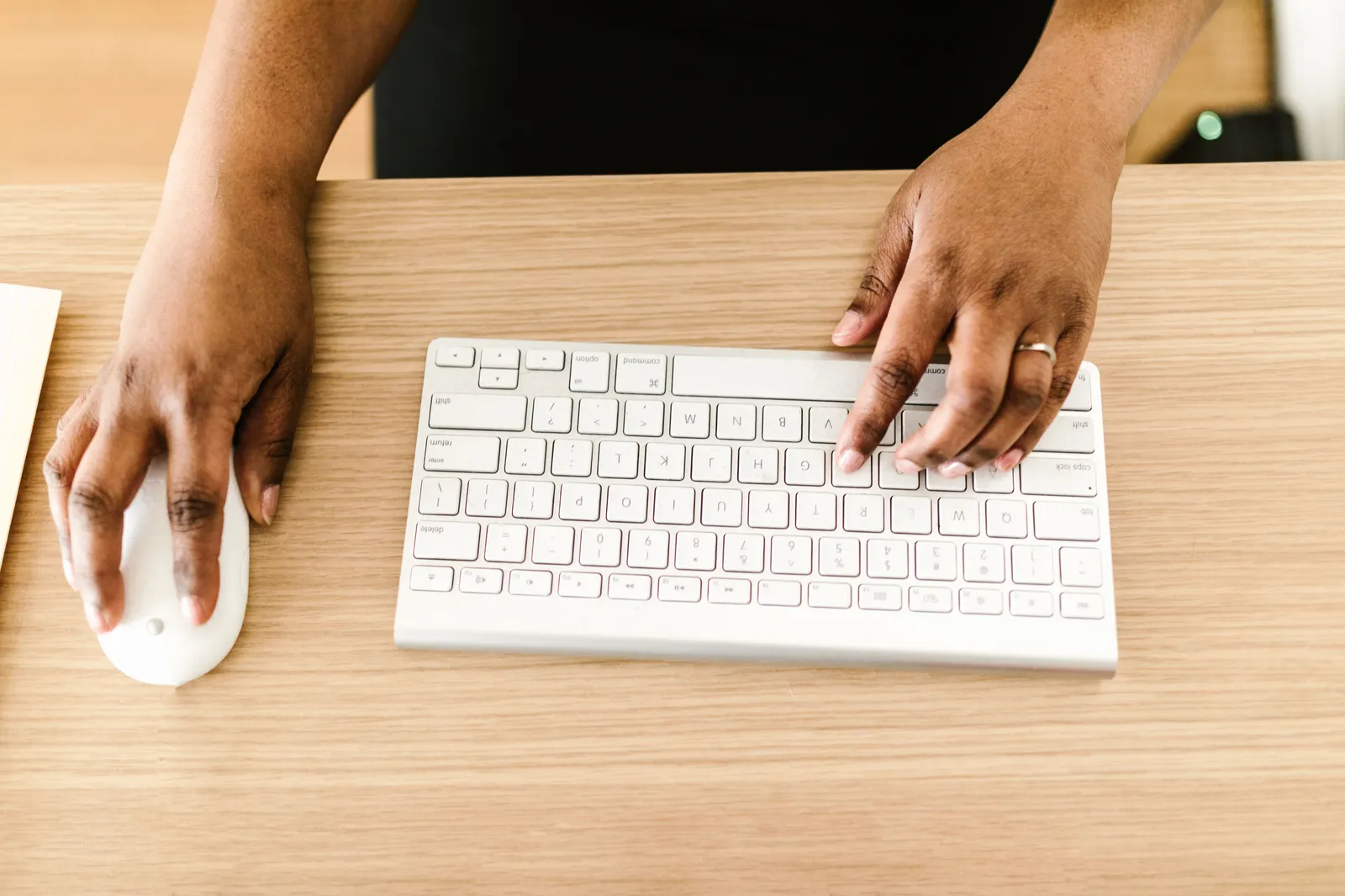 Hands typing on a white keyboard on wooden desk, ideal for business or tech themes