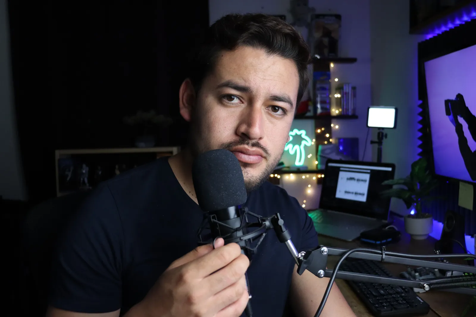 Man in a studio setting, talking into a microphone with a focused expression