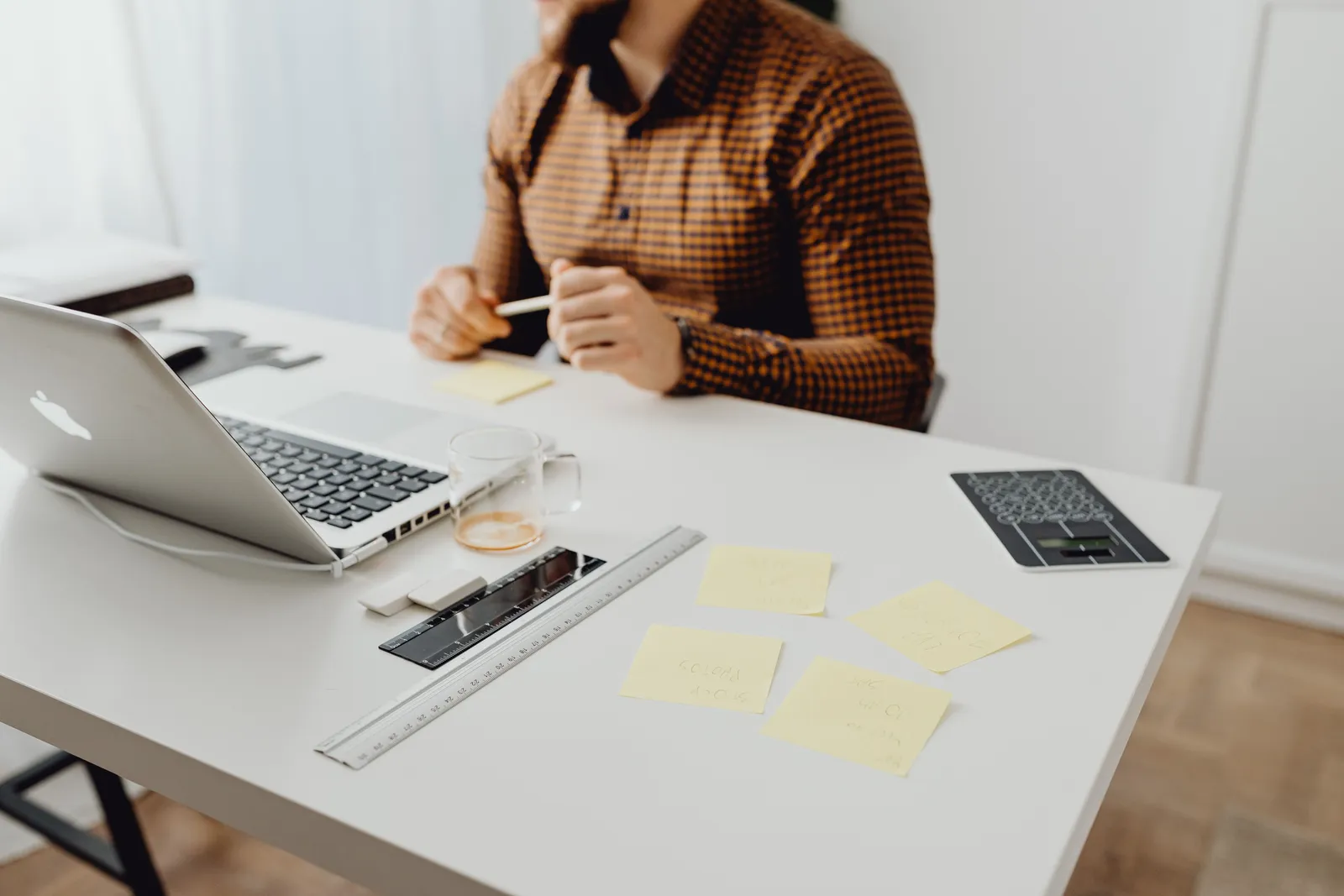 Modern workspace setup with laptop, office supplies, and a person in a checked shirt