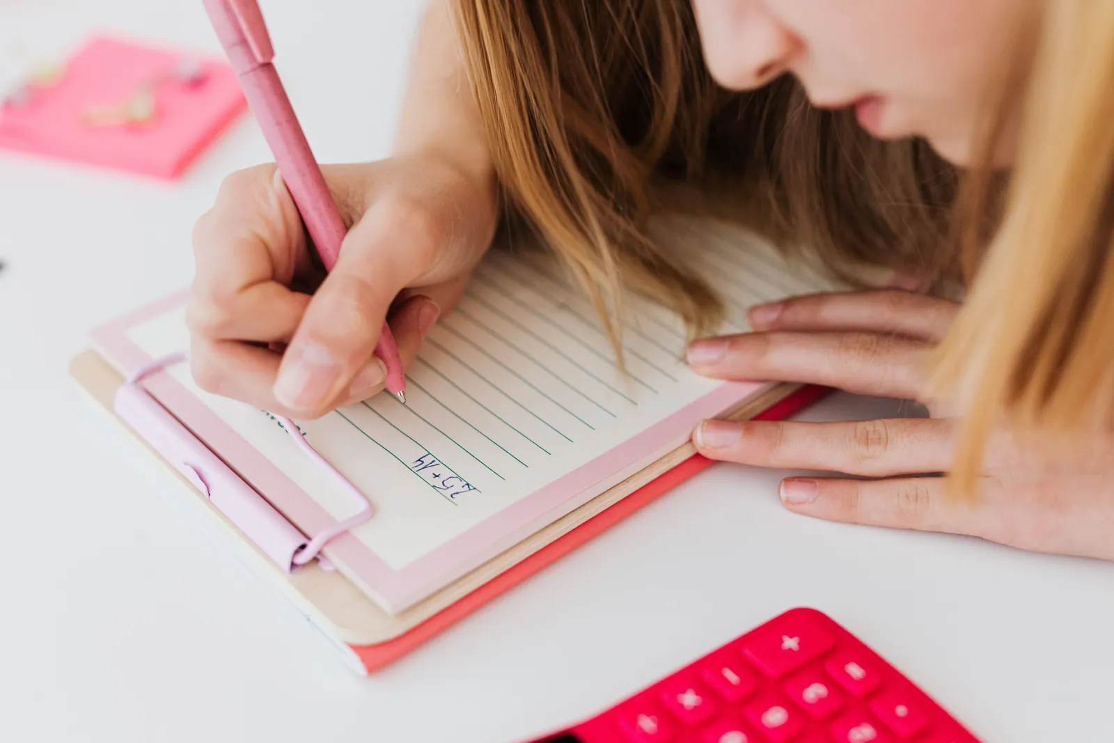 A woman concentrating while writing notes on a clipboard with a pink pen