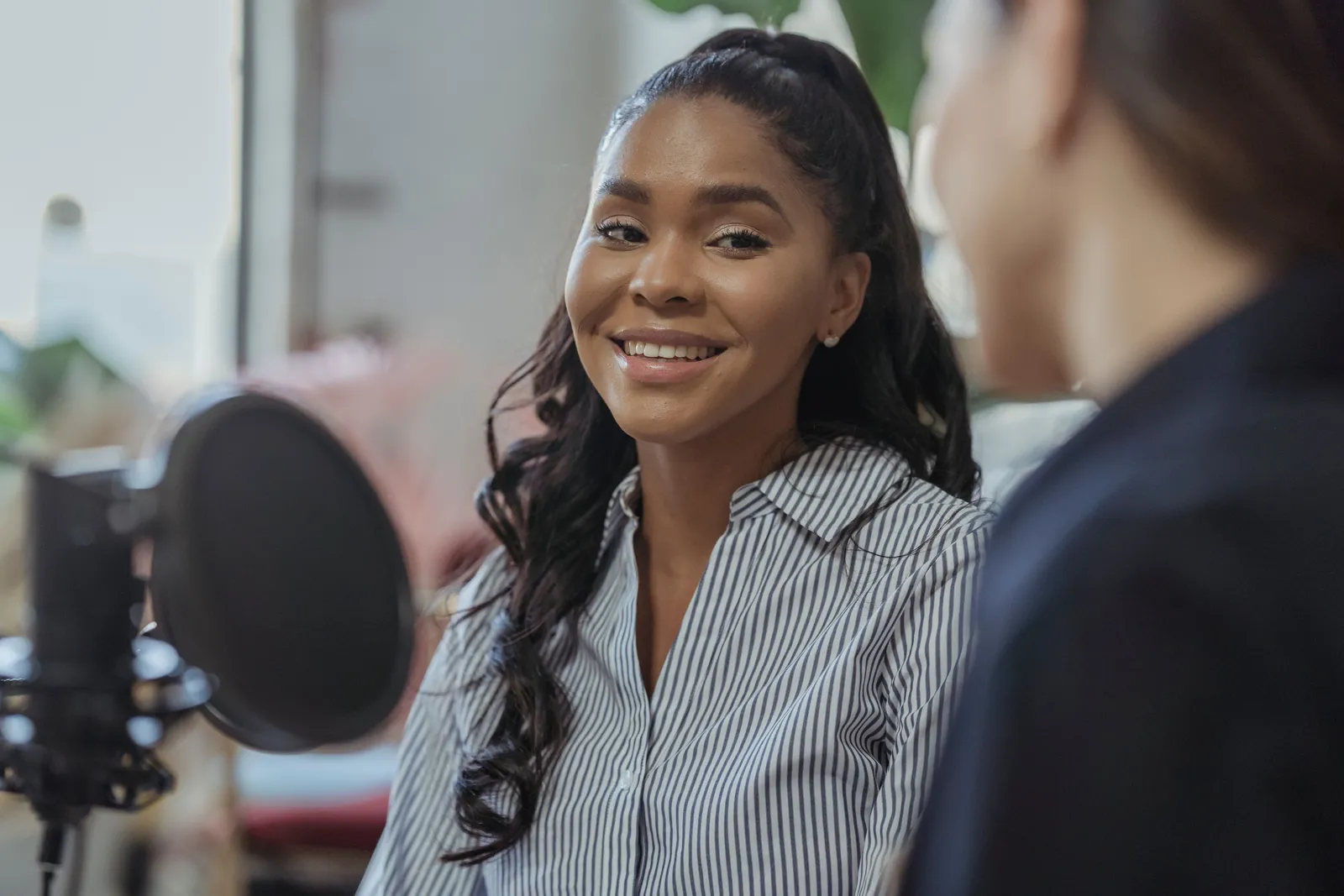 Close-up of a smiling woman during a podcast recording indoors