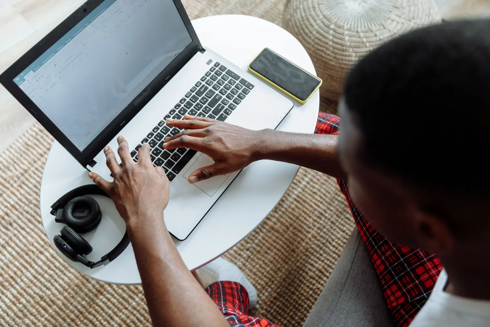 Top view of a man typing on a laptop, with a smartphone and headphones on the desk
