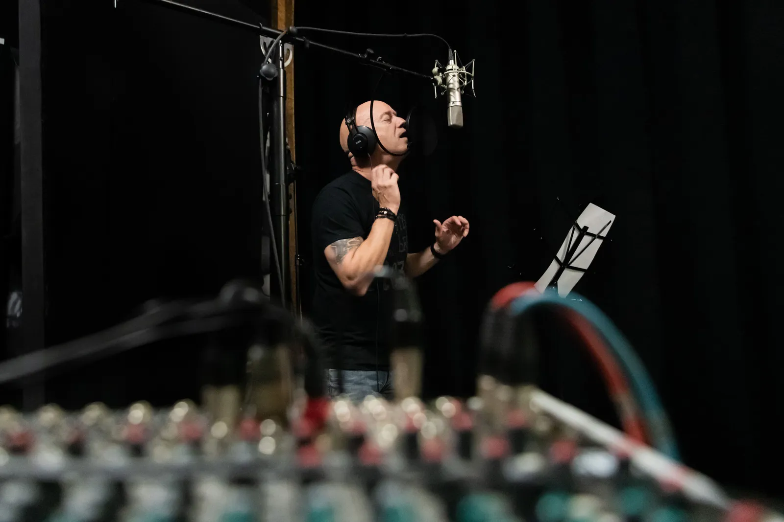 A vocalist intensely performing in a professional recording studio setting