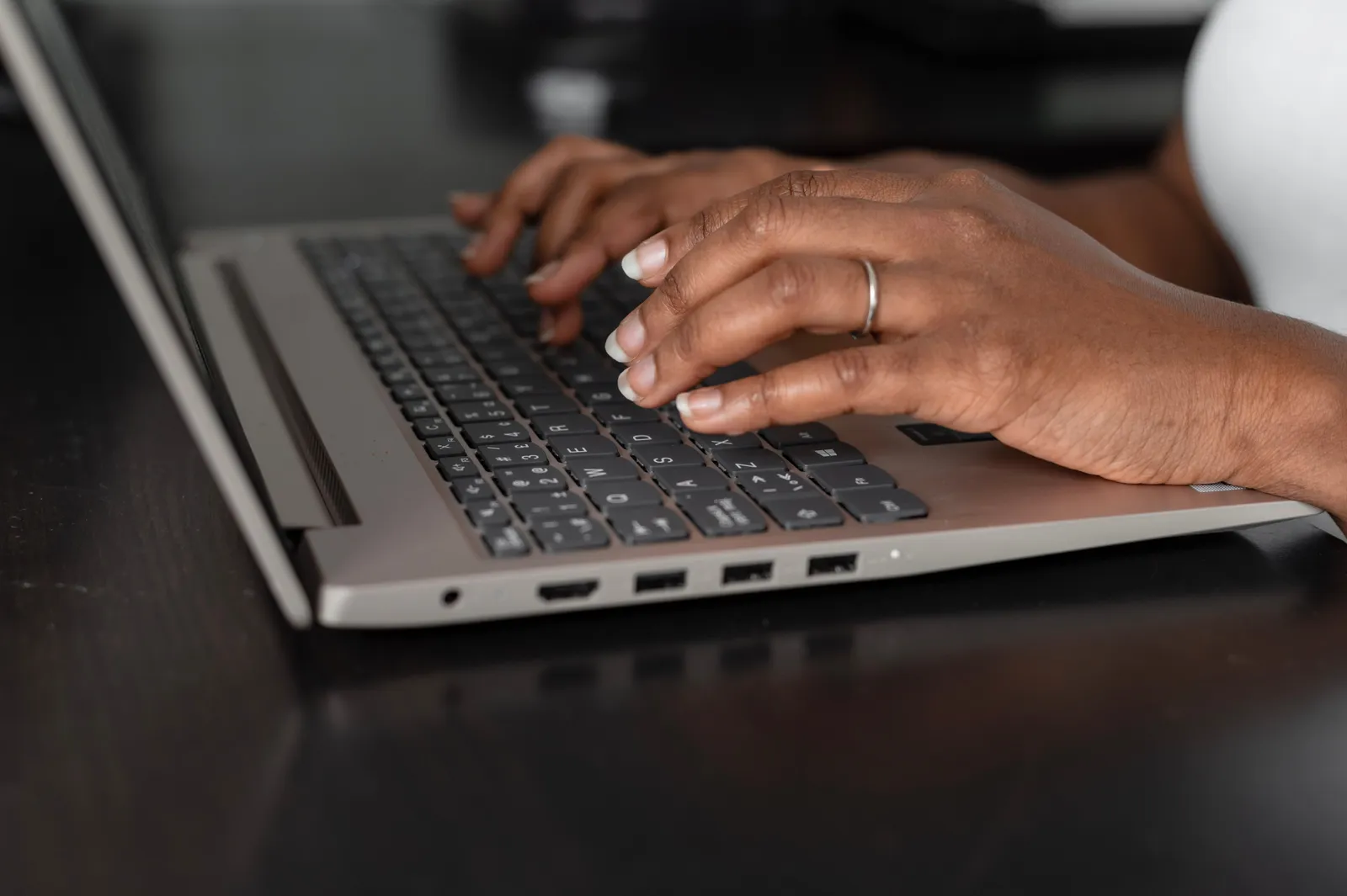 A close-up view of hands typing on a laptop keyboard in a modern workspace