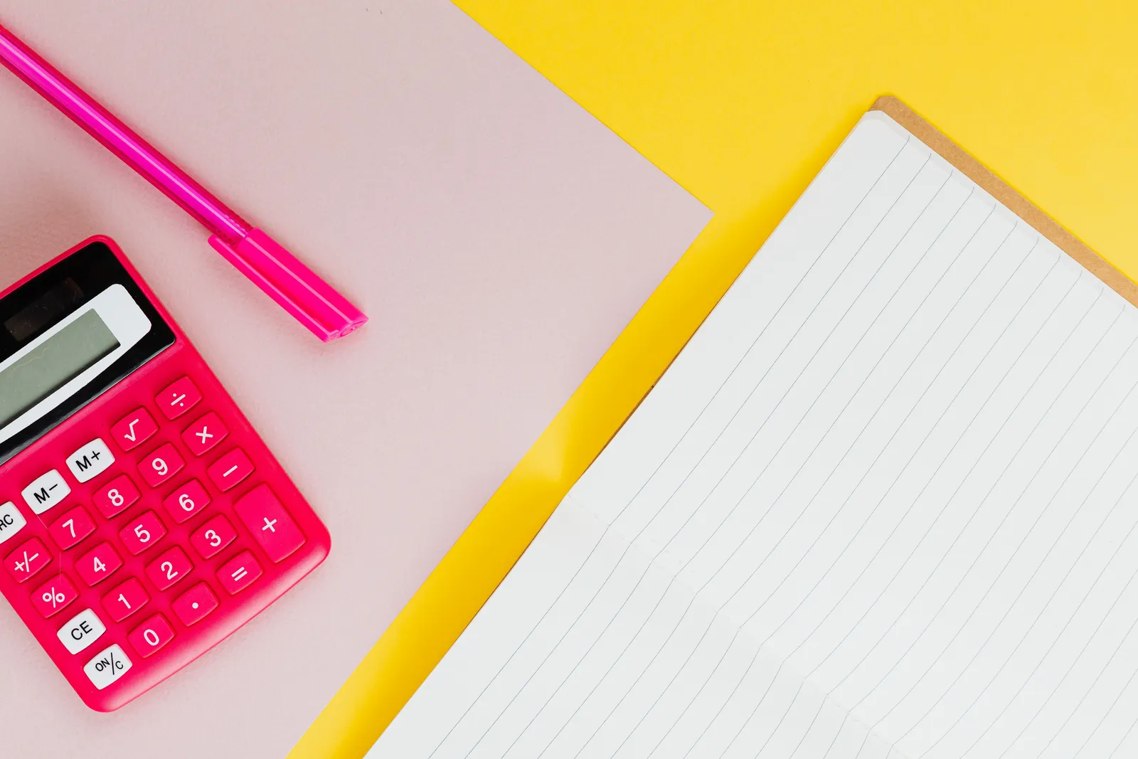 Vibrant pink calculator and pen on a colorful background with a lined notebook for office or school use