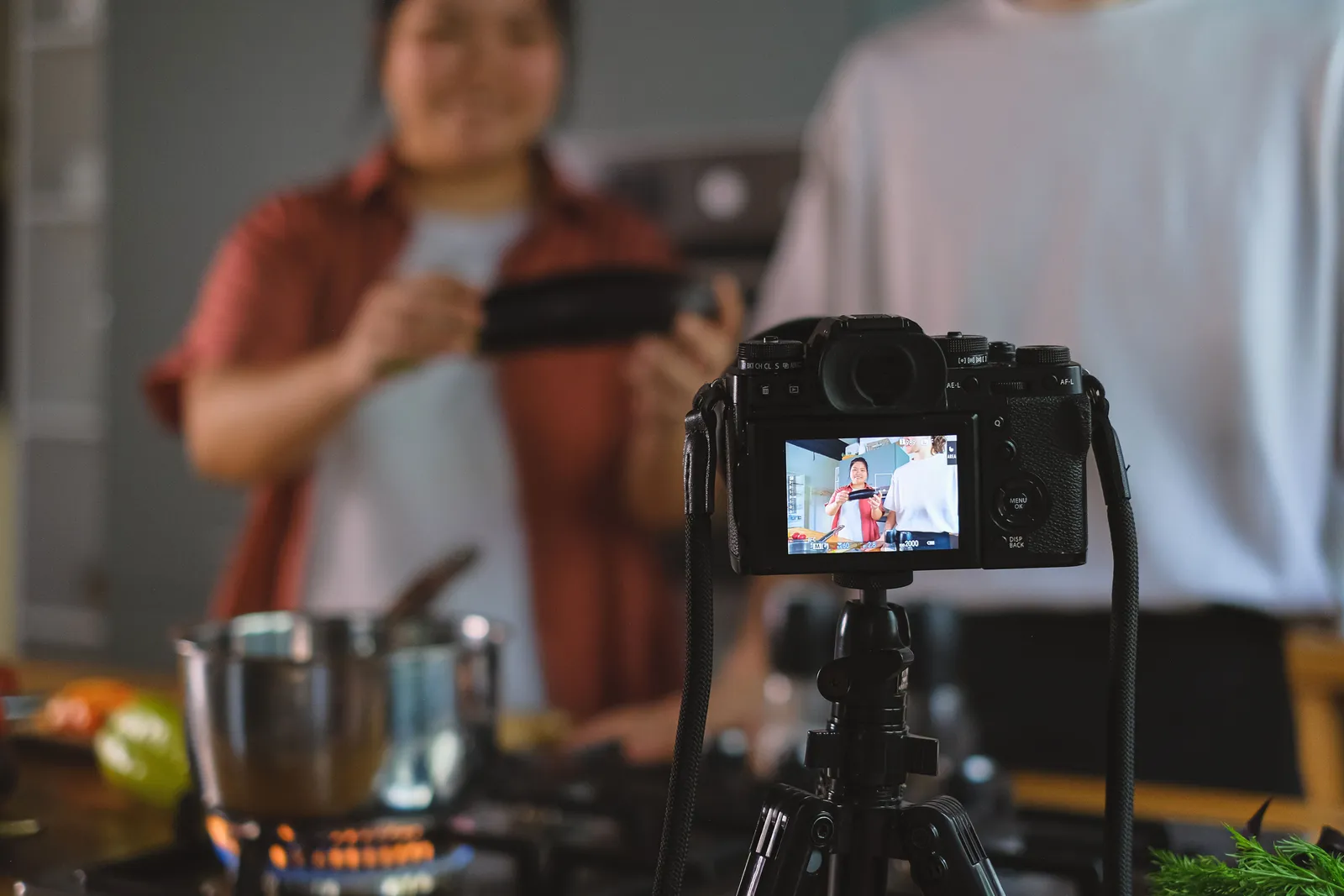 Behind-the-scenes setup of cooking video using a tripod-mounted camera in a kitchen