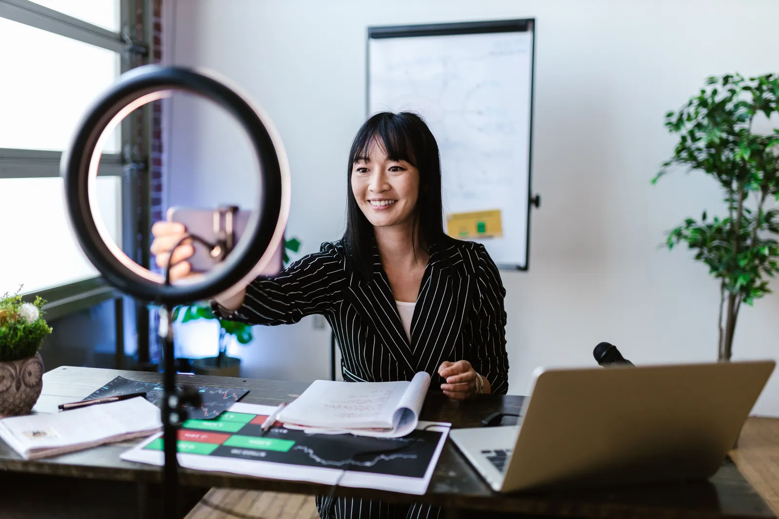 A woman vlogger uses her smartphone to create content in a professional office setting