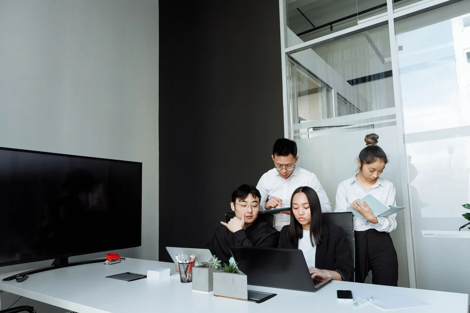 Team of young professionals collaborating in a modern office setting, engaging with laptops and documents