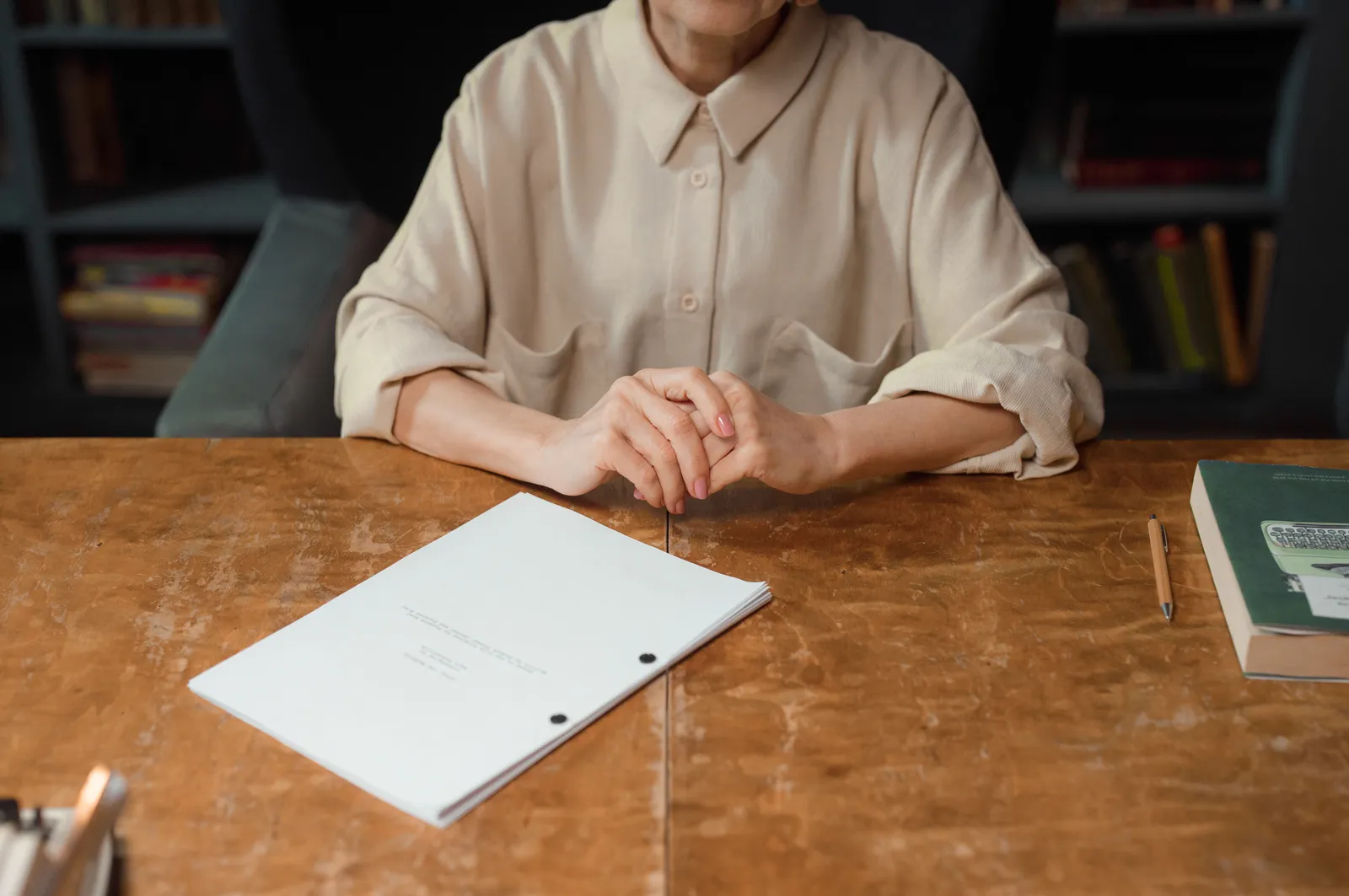 Woman sitting at wooden desk reviewing a screenplay in an office setting