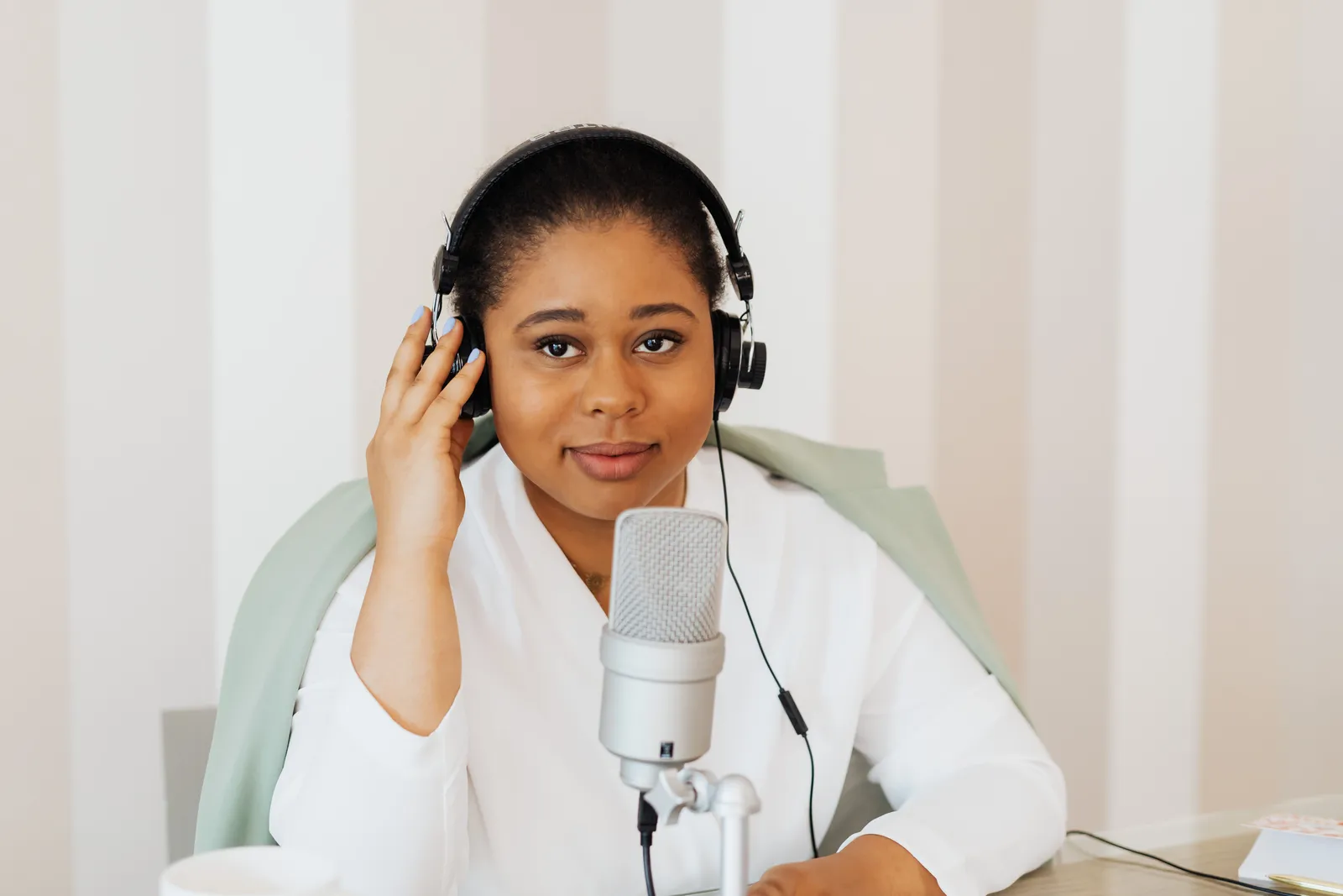 Young woman podcaster with headphones at a desk using a microphone