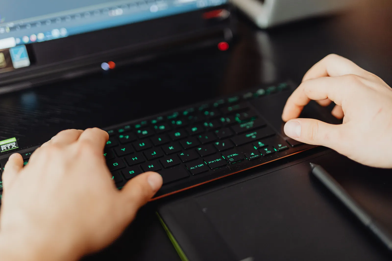 Closeup of hands typing on an RGB keyboard in a modern office setting