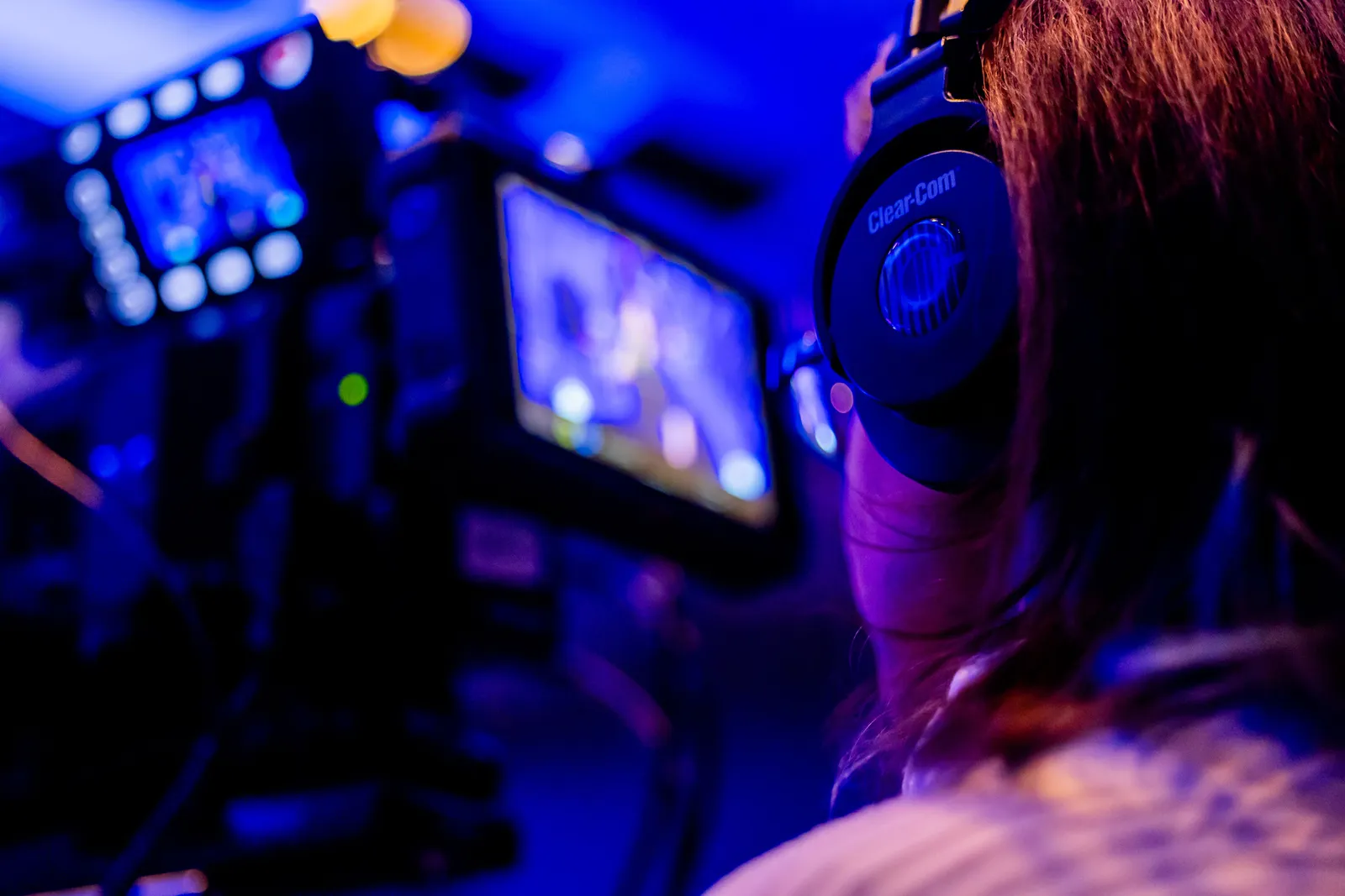 A person wearing headphones operates a camera in a vibrant studio environment