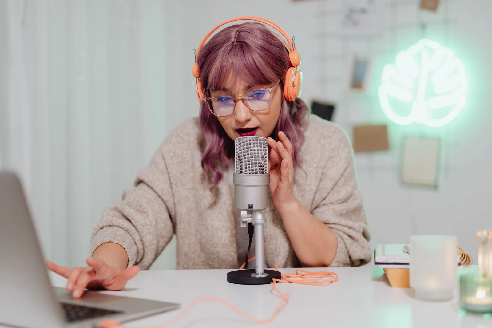 A young woman recording a podcast indoors with a microphone and headset, focused and engaged