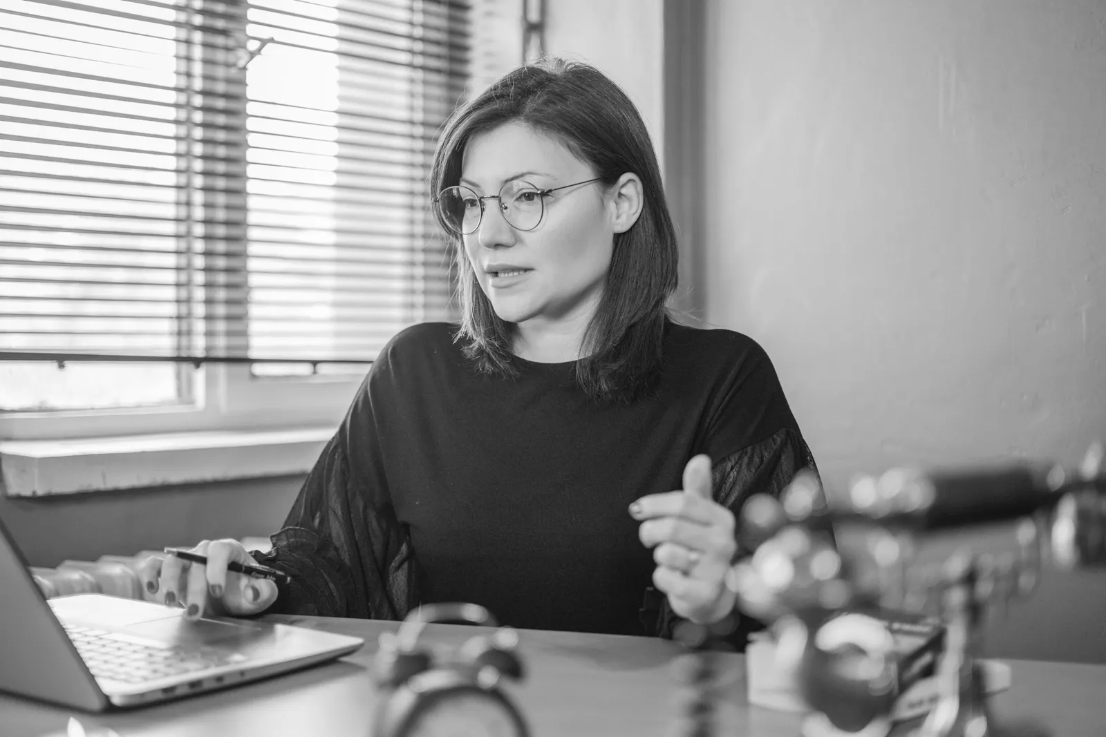 Black and white portrait of a woman using a laptop at a desk, engaging in a video call