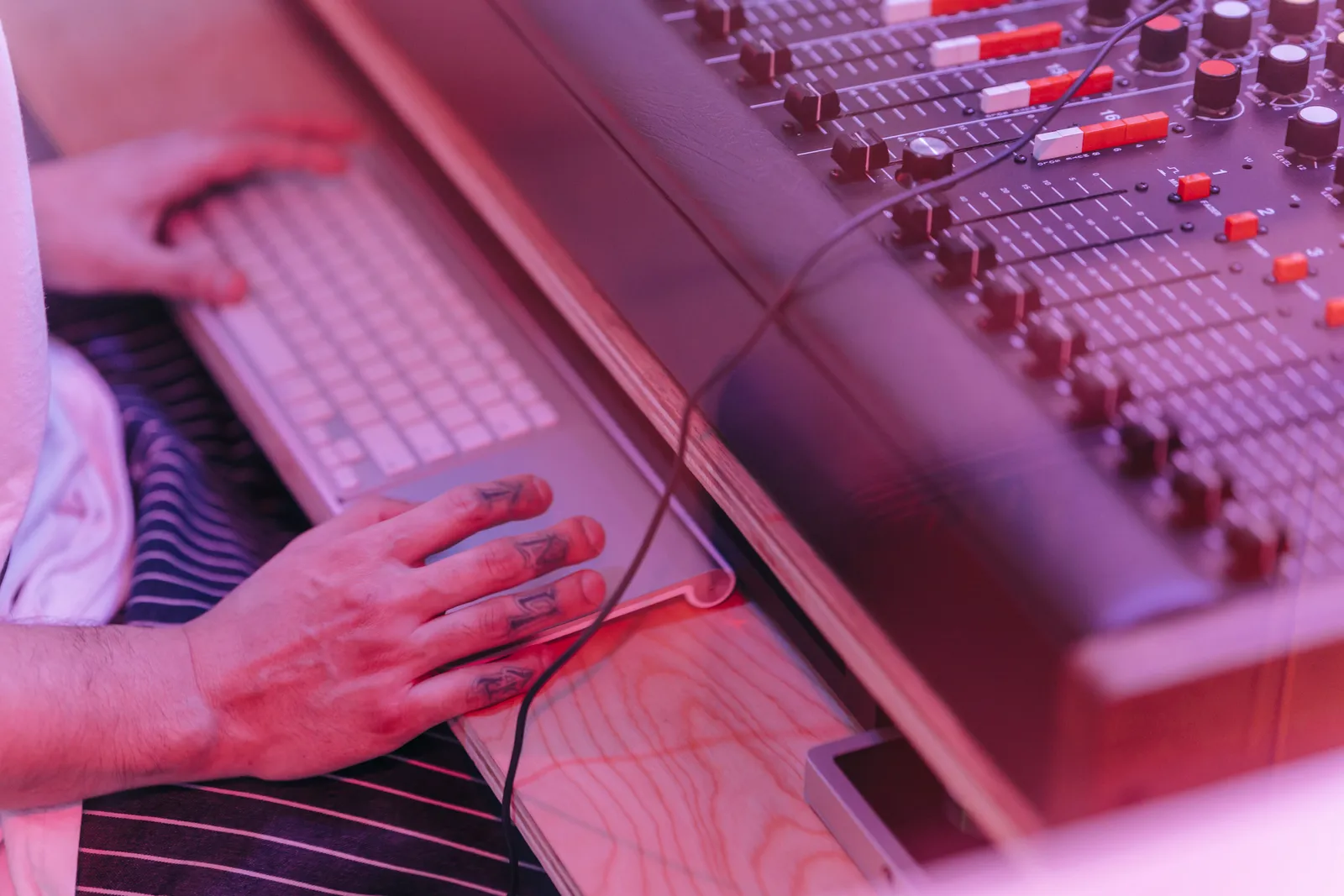 Close-up of hands working at a sound mixer and keyboard in a recording studio