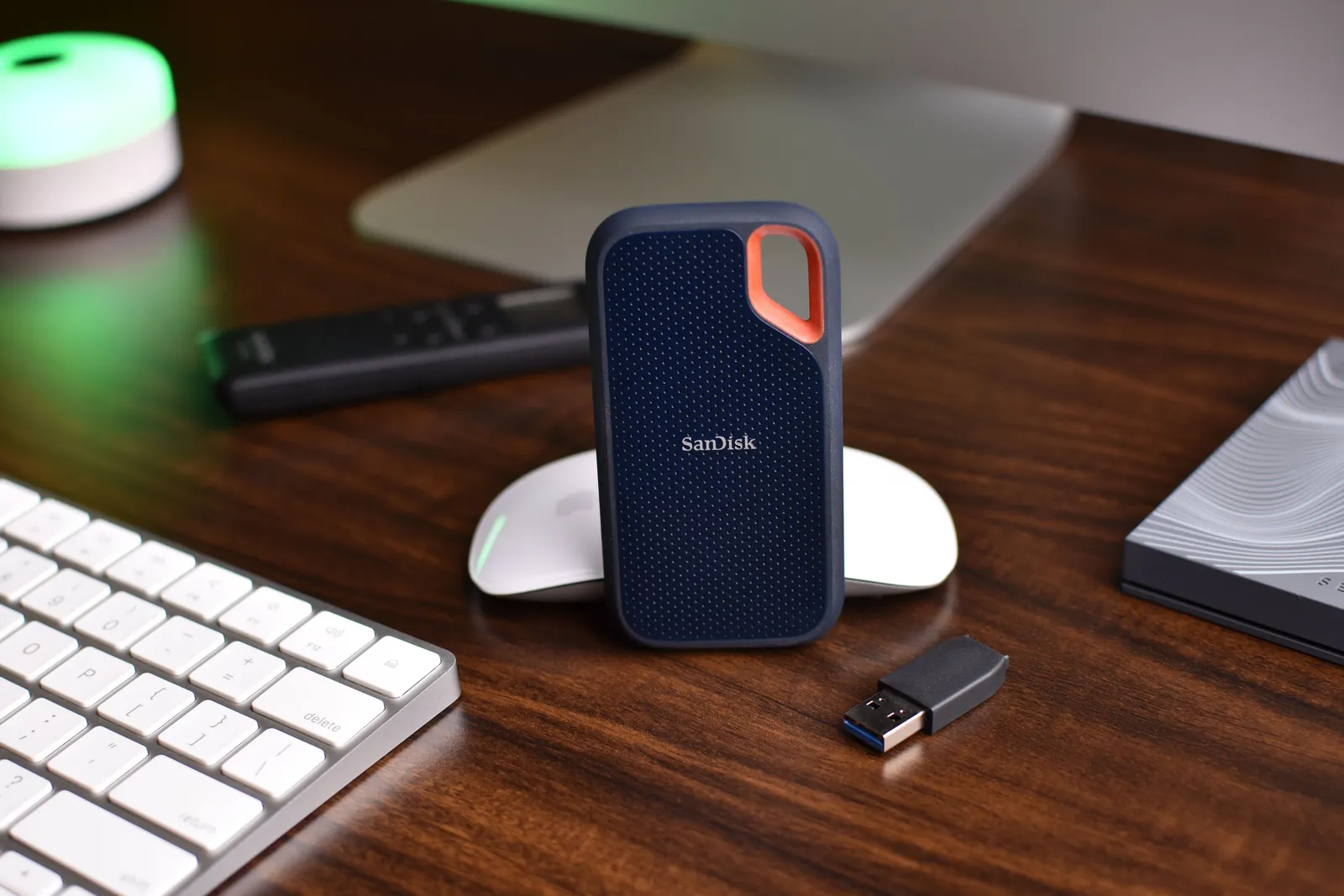 Close-up of a desk setup featuring a SanDisk SSD, keyboard, and USB drive, highlighting modern technology