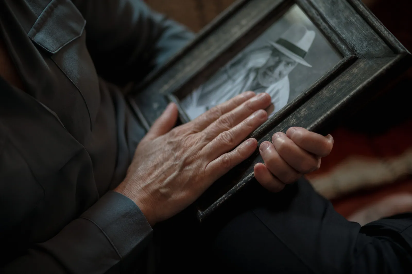 A close-up shot of hands gently holding a vintage framed photograph, evoking nostalgia and memories