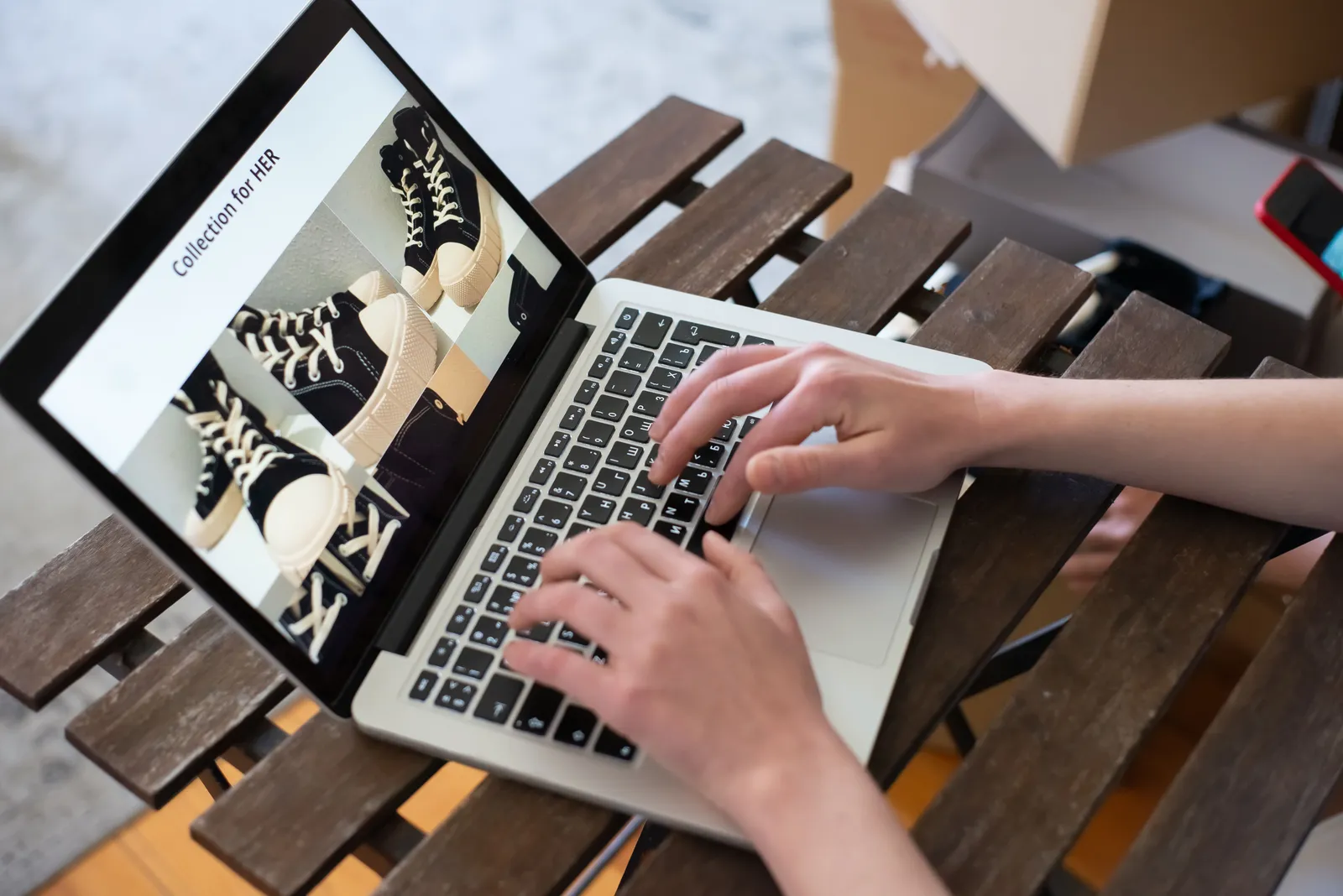 Hands of a person browsing a Collection for HER on an online shoe store using a laptop