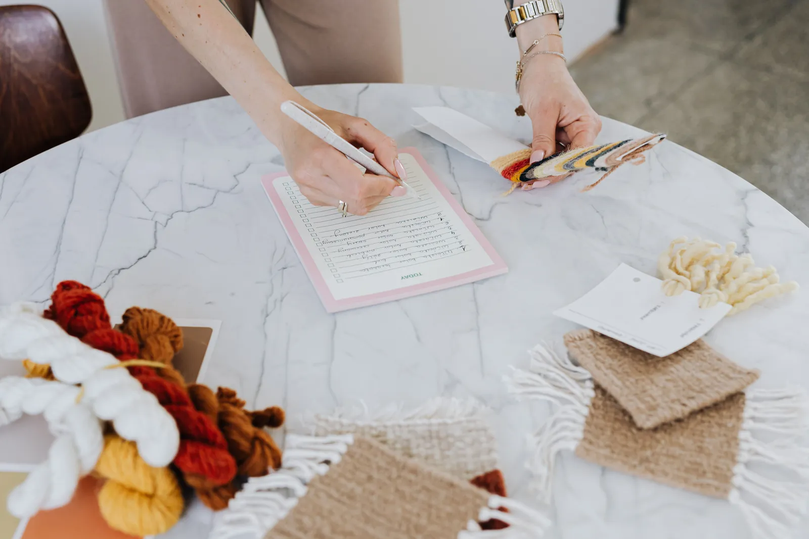 Close-up of hands working with wool and swatch samples on a marble desk