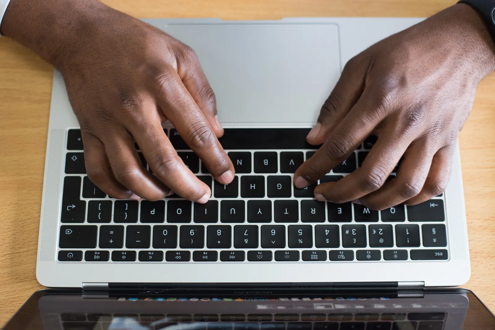 Hands typing on a laptop keyboard, showcasing modern technology in an indoor workspace