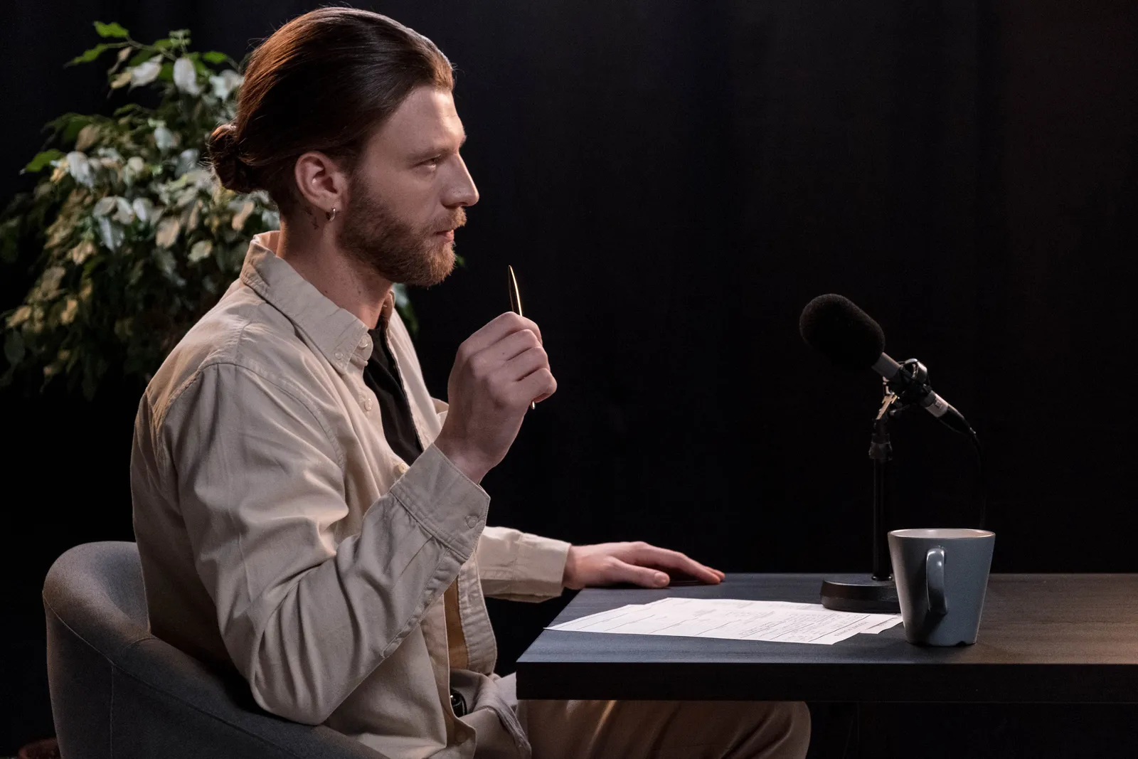 A man recording a podcast in a professional studio environment, engaging with a microphone