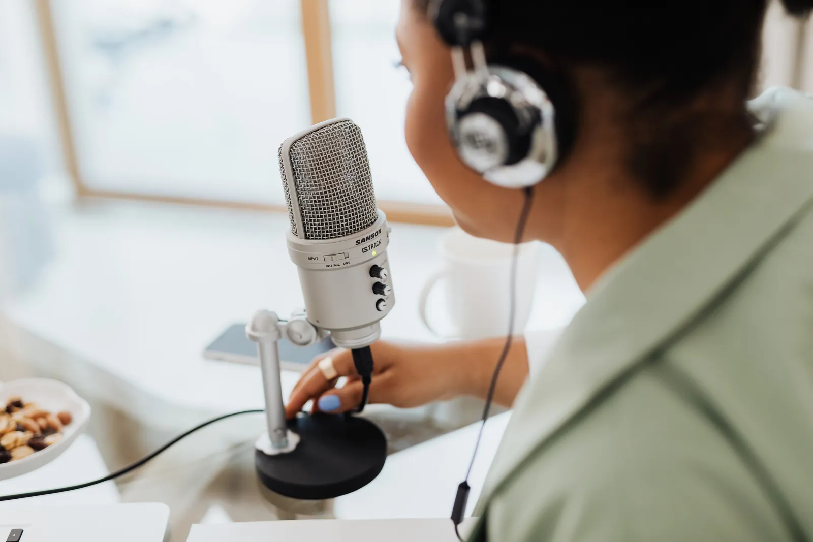 Woman using a microphone and headphones indoors, focusing on recording a podcast or voiceover