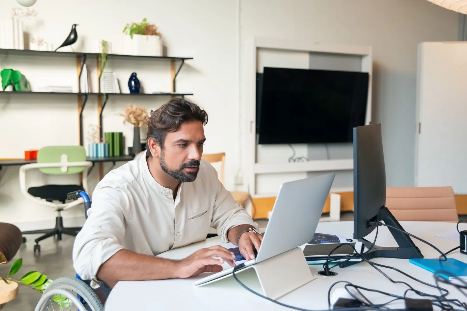 Professional man using a laptop in a modern office setting, showcasing accessibility and business environment