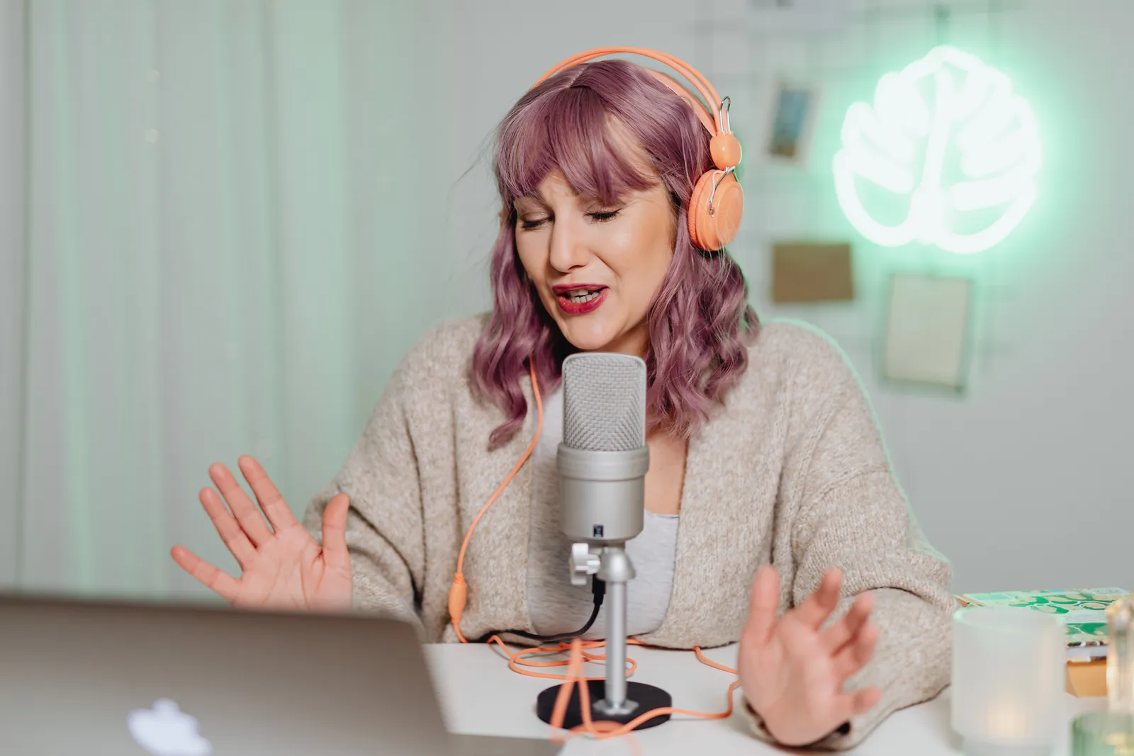 Woman podcasting indoors with headphones and microphone, engaging in recording or live stream