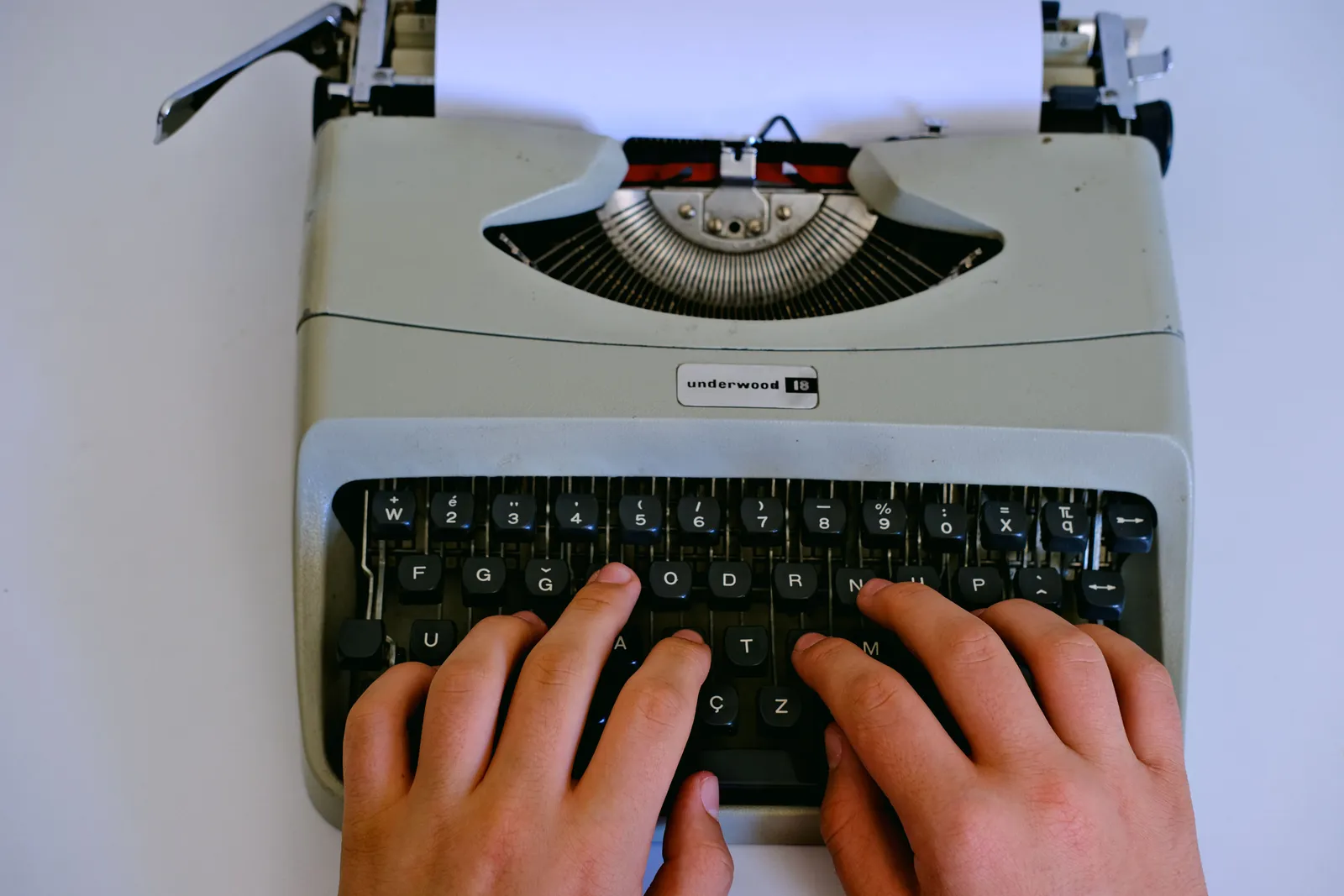 Close-up of hands typing on a classic Underwood typewriter with paper