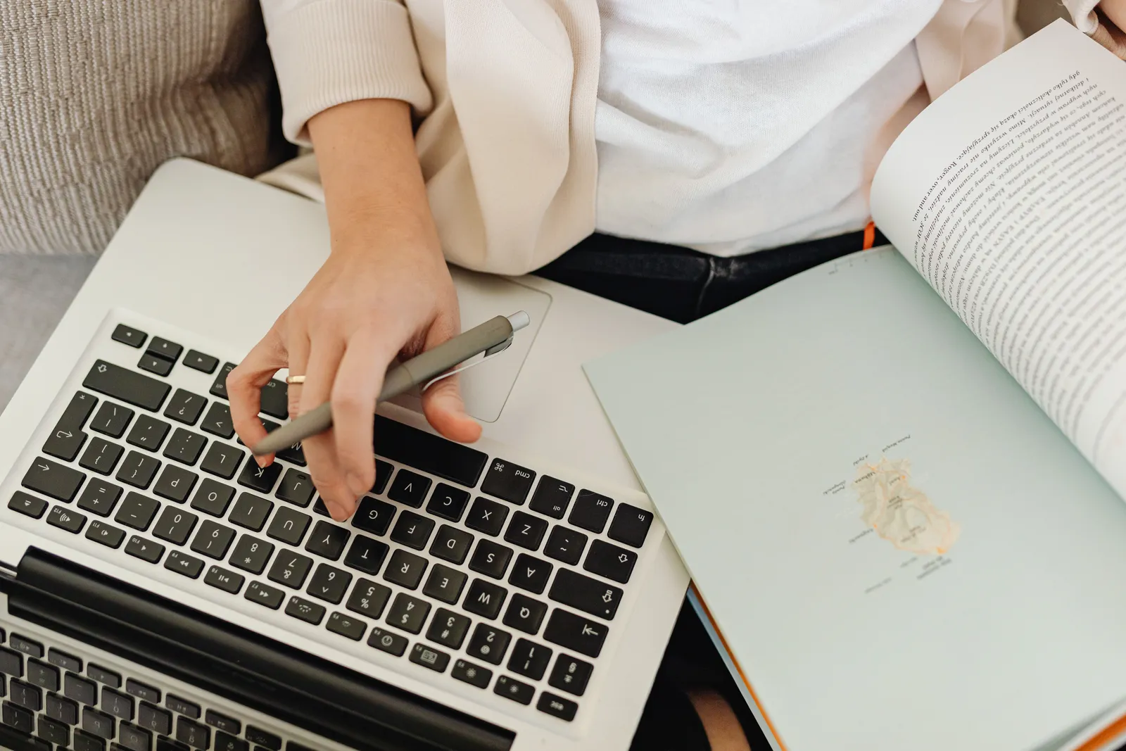 Close-up of a person working on a laptop and reading an open book. Ideal for educational themes