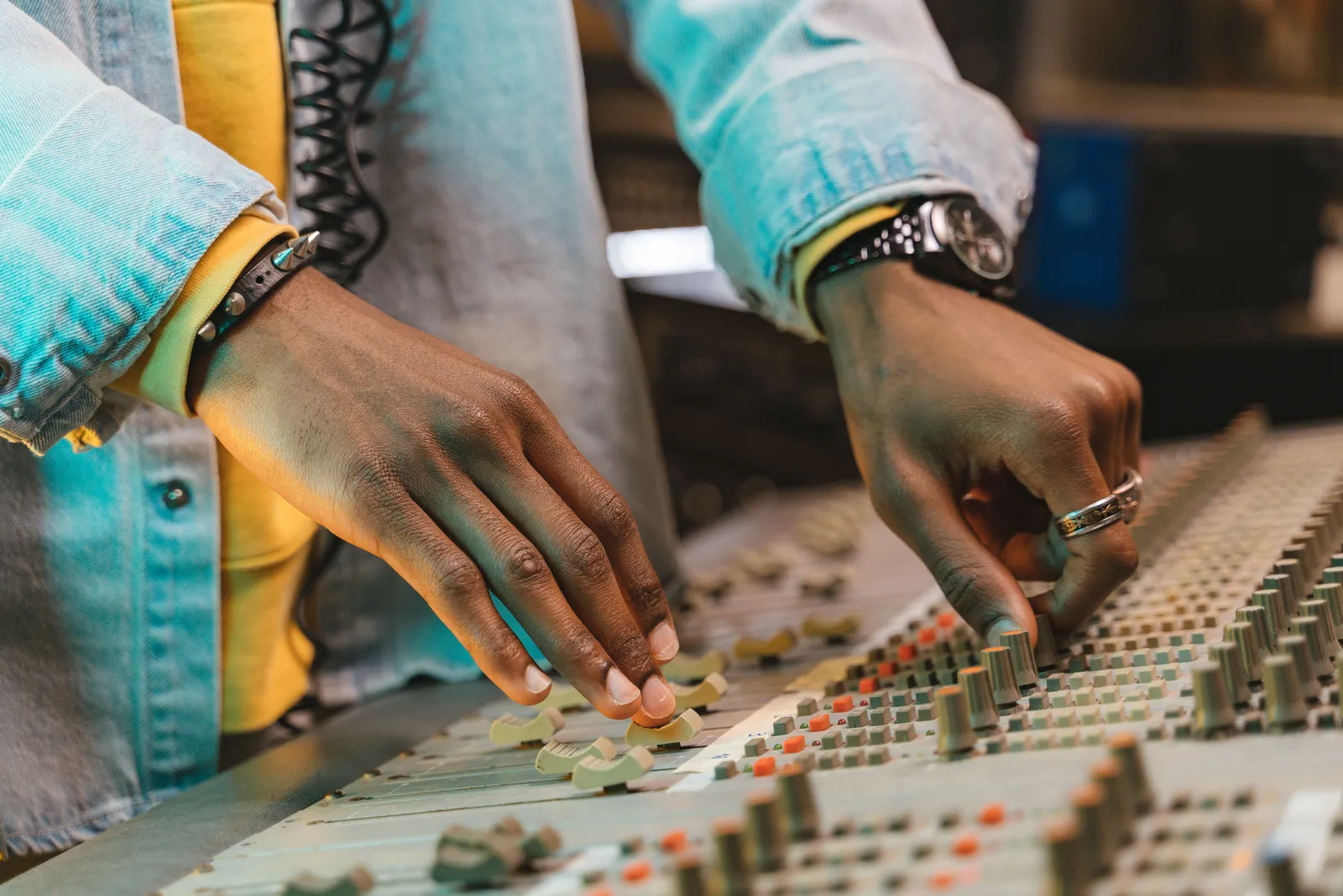 Hands adjusting an audio mixer in a studio environment, showcasing precision and focus