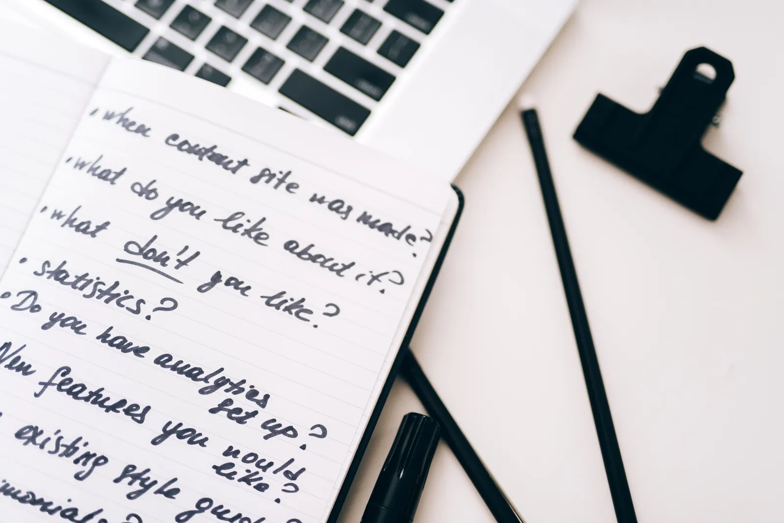 A close-up view of a notebook with handwritten notes alongside a laptop for planning and strategy