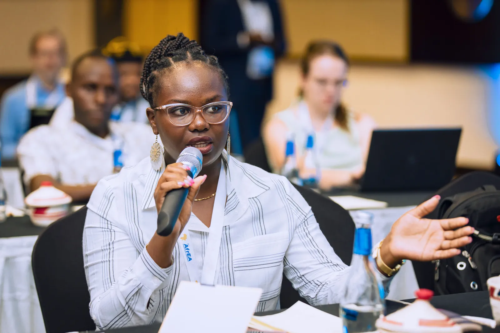 Woman speaking into a microphone during a business conference, engaging with audience