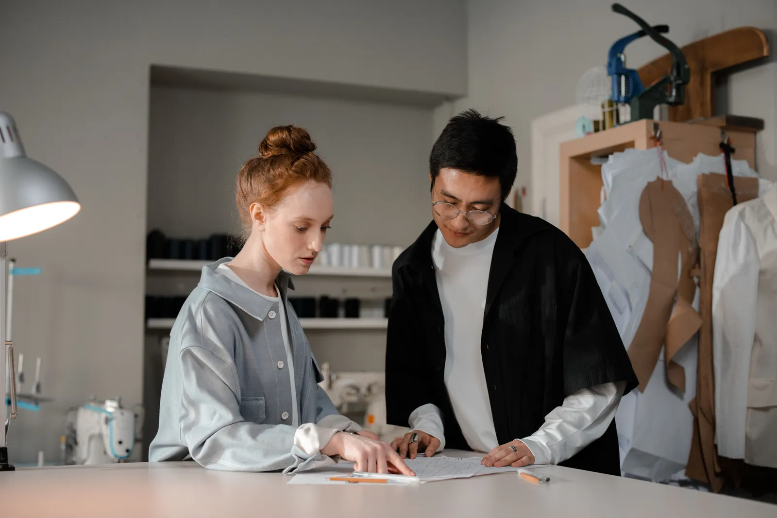 Two designers collaborate in a stylish fashion studio, focusing on their creative work
