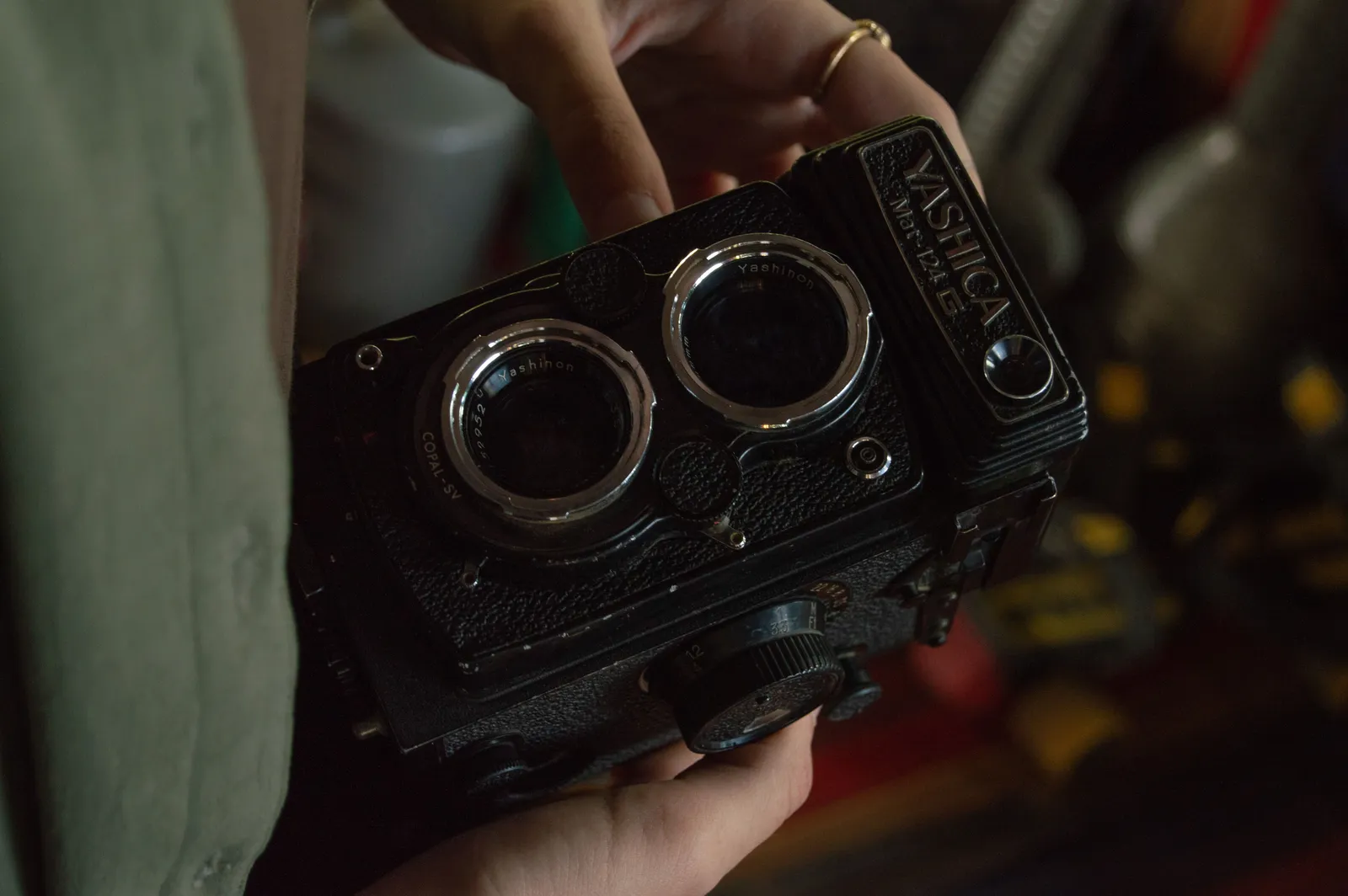 A detailed view of hands holding a classic Yashica twin-lens reflex camera, highlighting its retro design