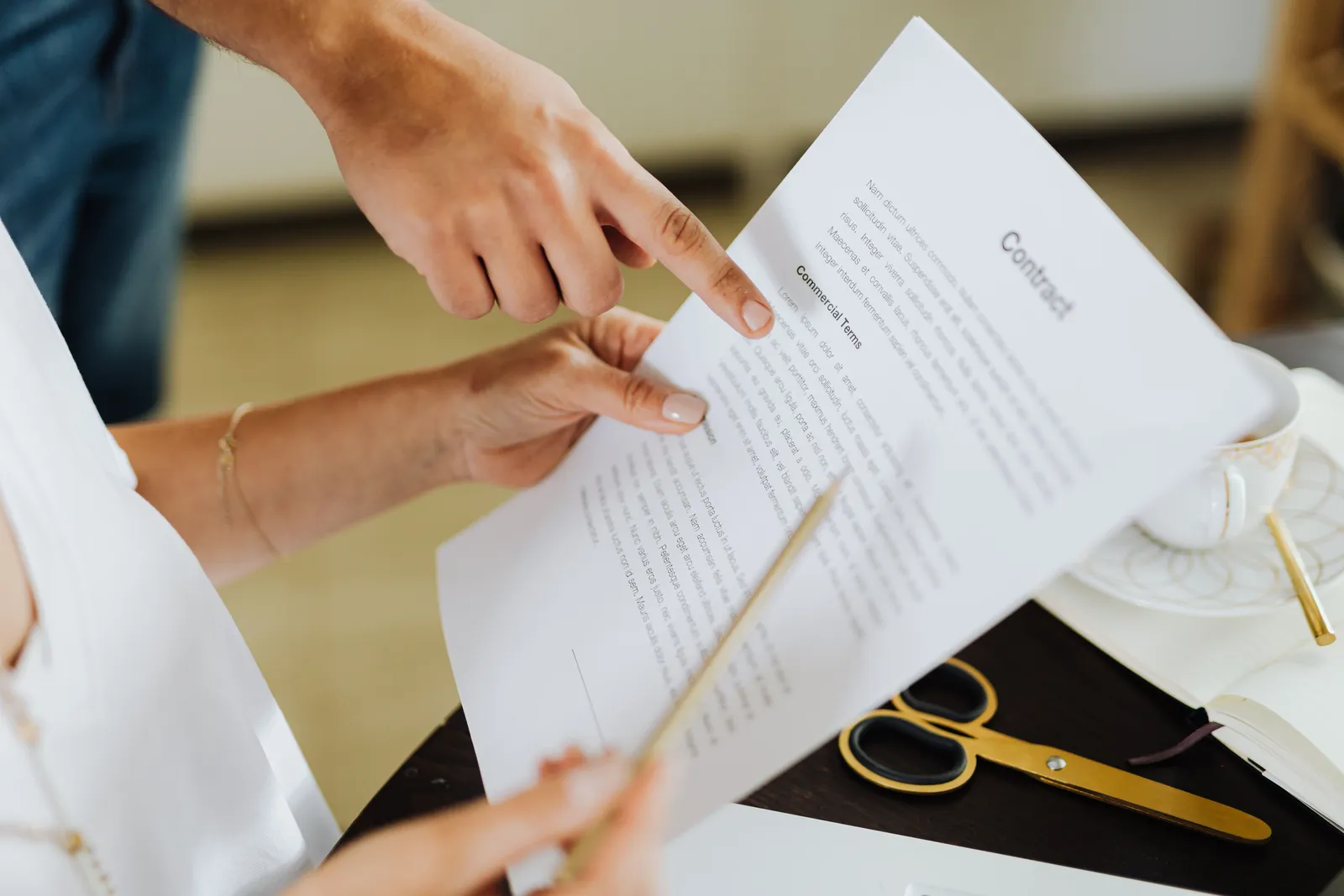 Close-up of two people discussing a business contract at a desk in an office setting