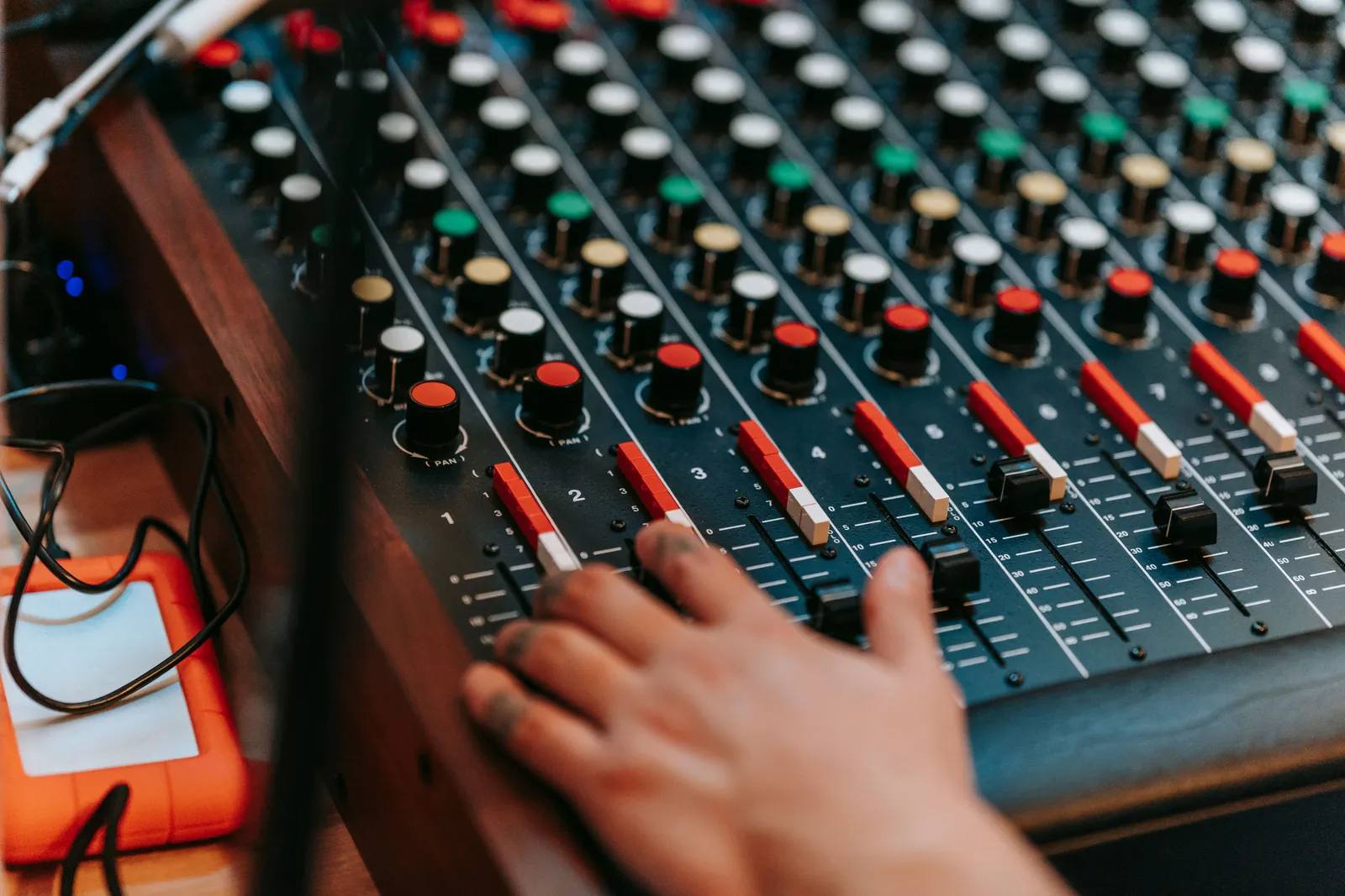 Close-up of a hand adjusting controls on a professional sound mixer in a recording studio