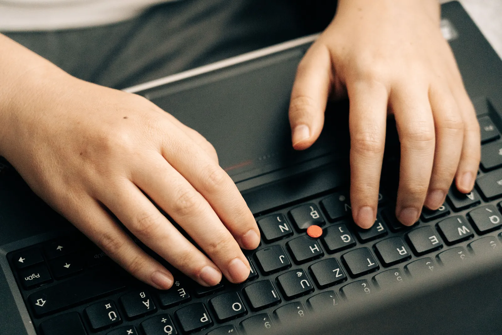 Close-up of hands typing on a black laptop's keyboard emphasizing productivity