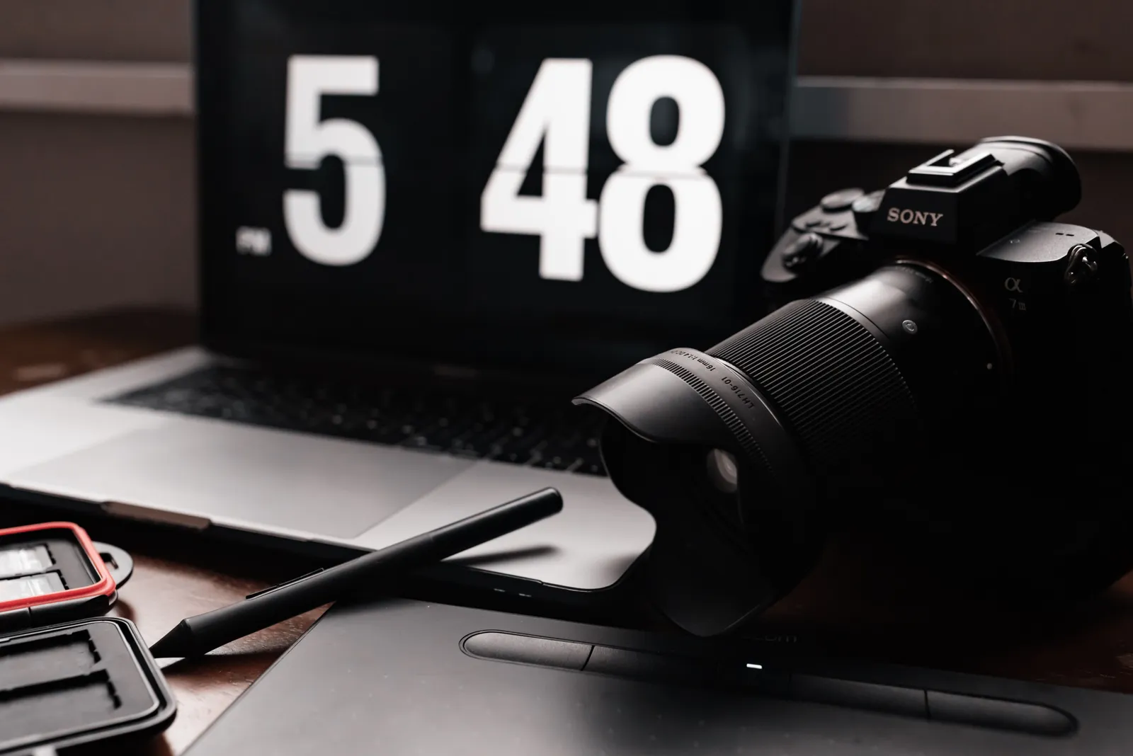 A stylish setup featuring a camera, laptop, and digital pen on a desk