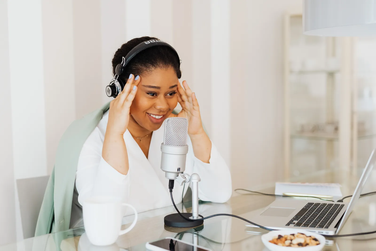 Woman in a home studio recording a podcast with a laptop and microphone