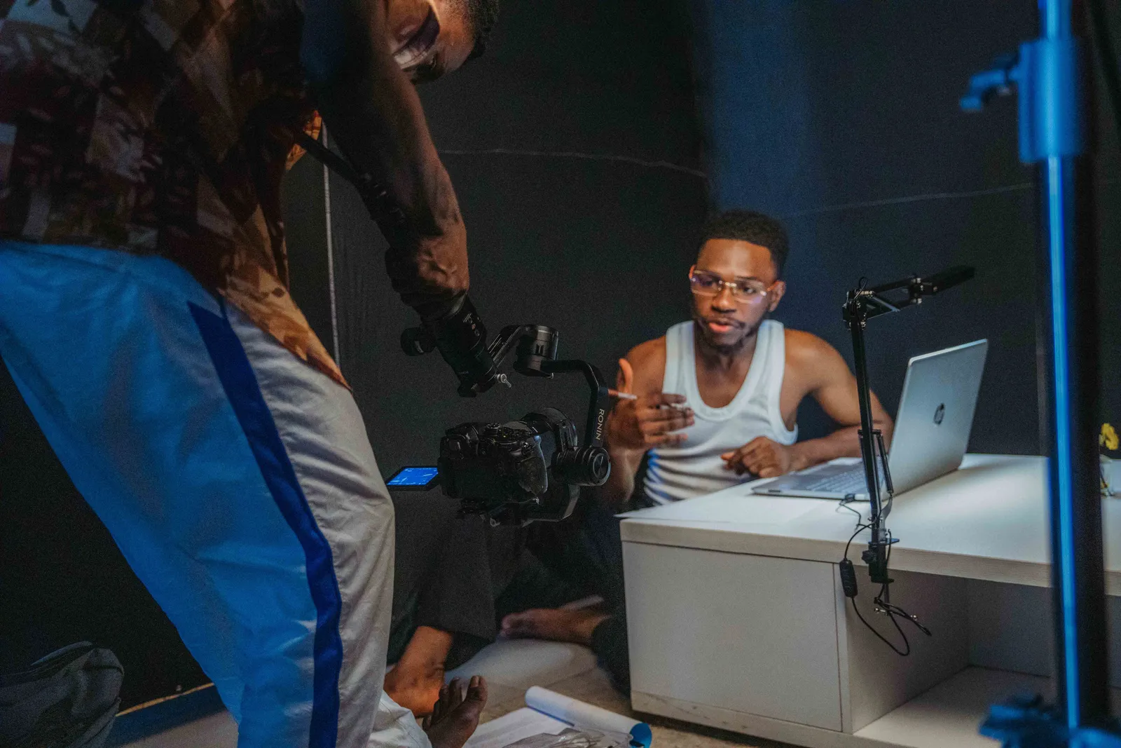 Young men filming a casual video with laptop and camera in a home studio setting