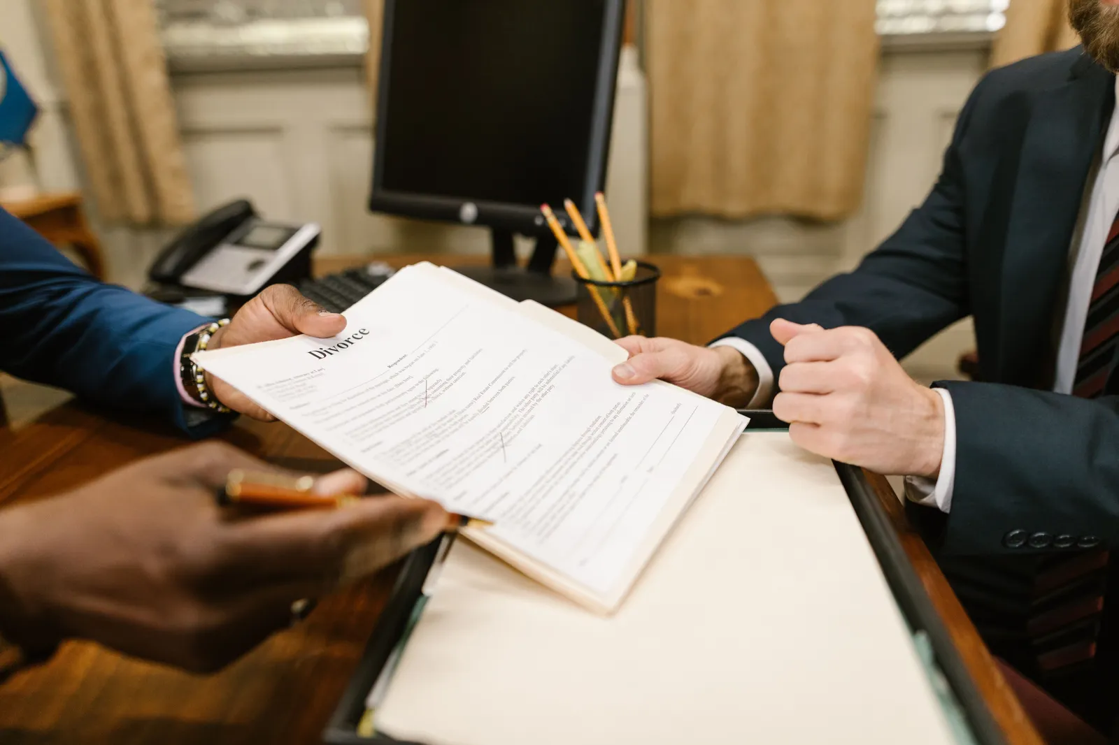 Close-up of hands exchanging divorce documents during legal proceedings in office