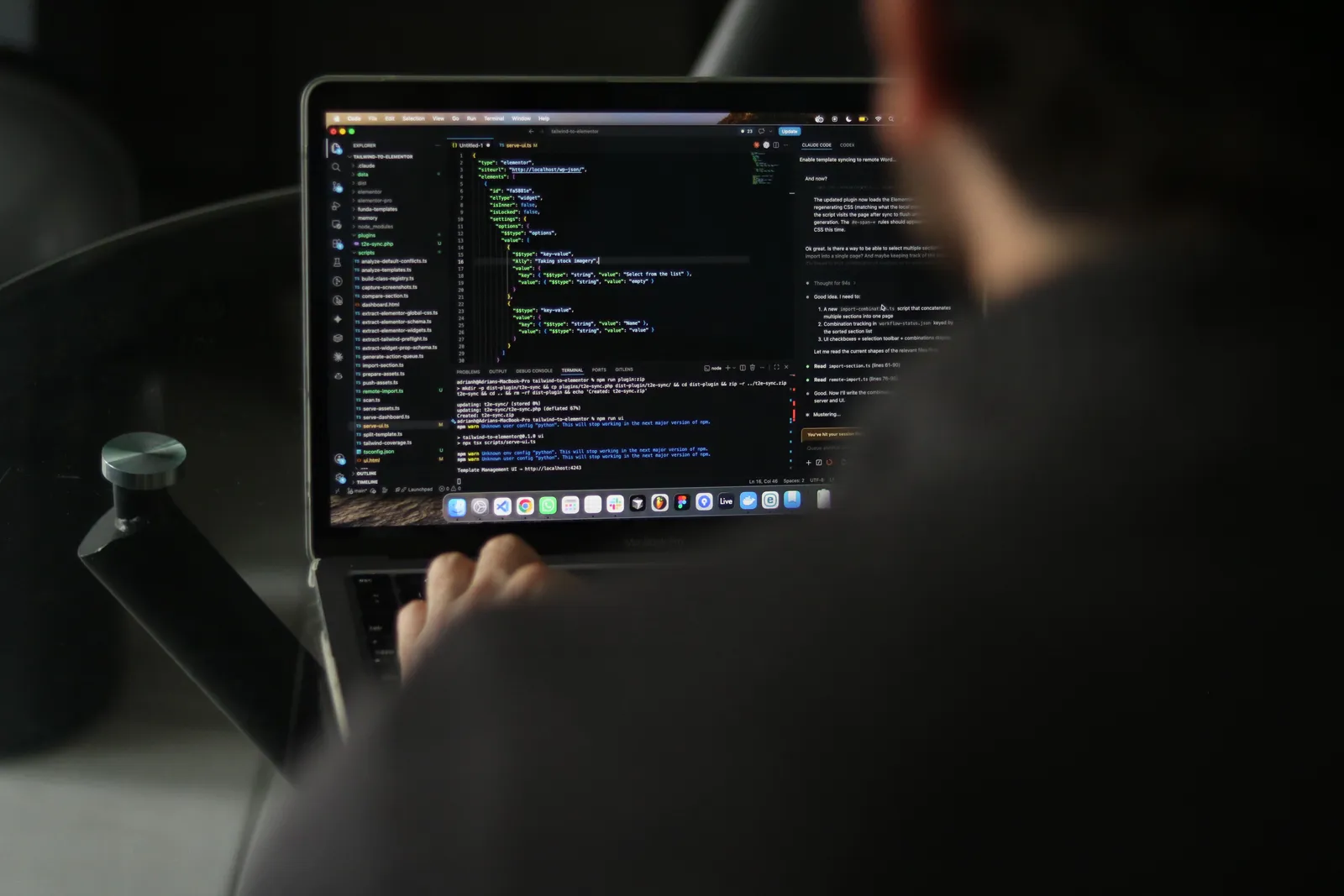 A focused developer writing code on a laptop in an indoor workspace